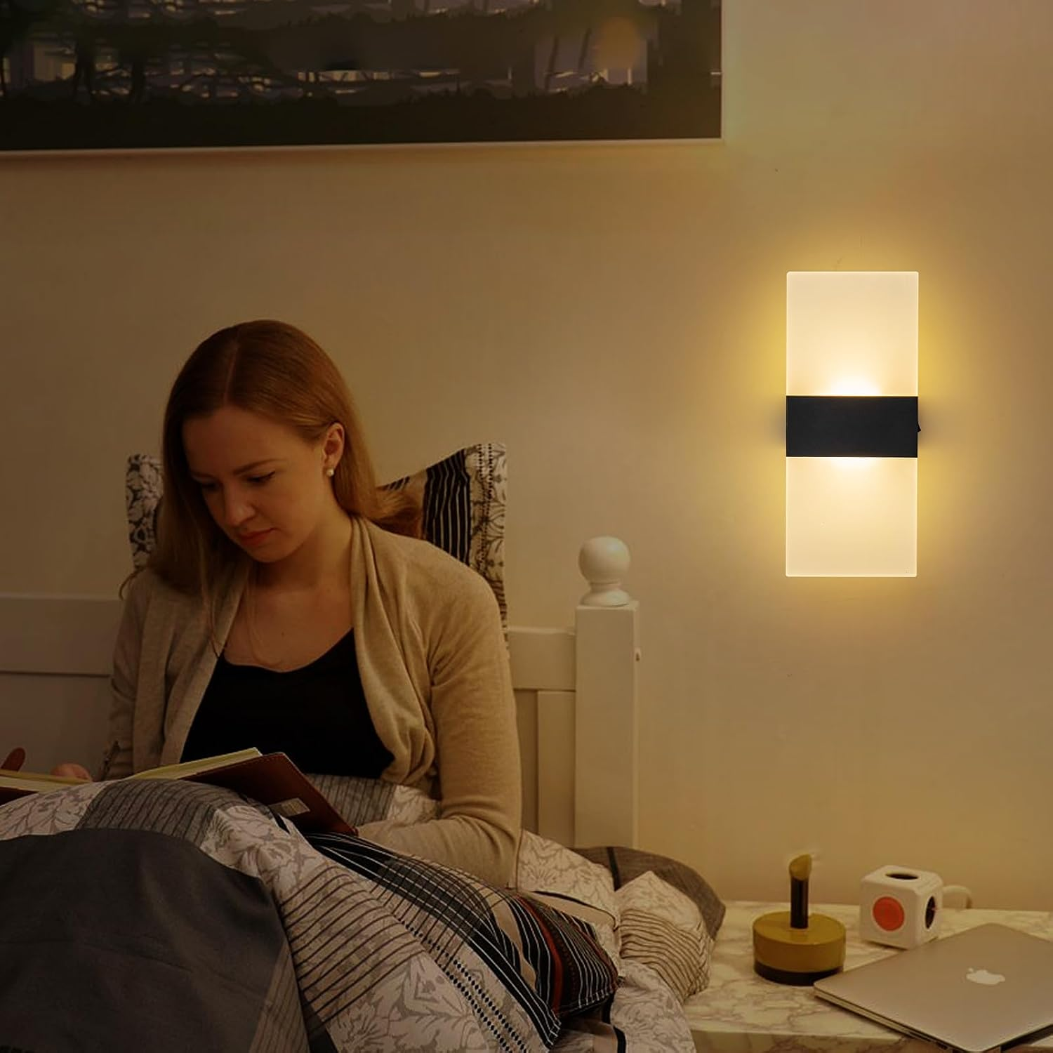 Eine Frau liest abends im Bett bei warmem Licht einer modernen Wandlampe.