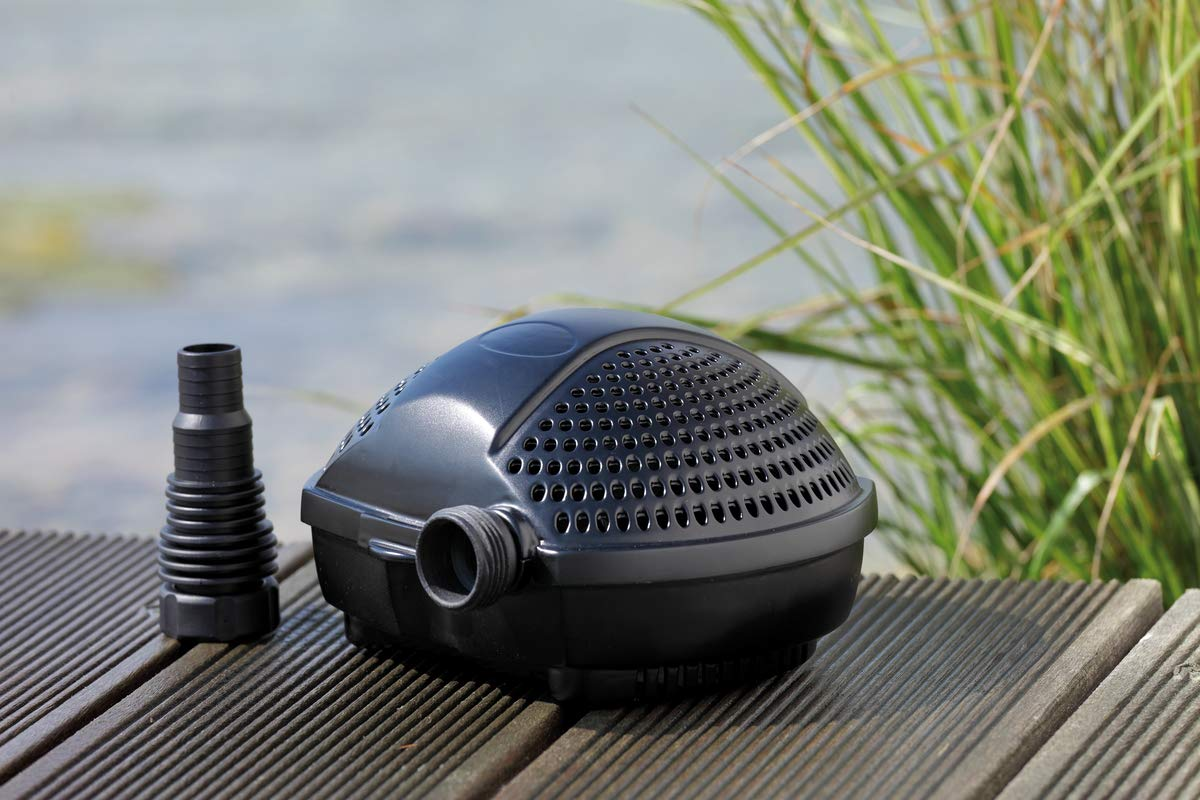Eine schwarze Teichpumpe mit Zubehör auf Holzplanken vor Wasser und Gras.