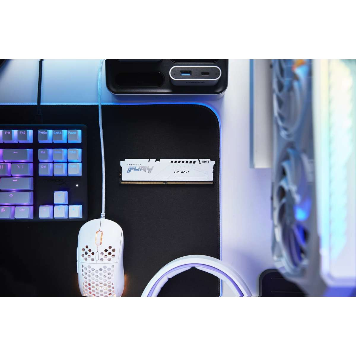 Ein weißer Kingston Fury DDR5 RAM-Stick liegt auf einem schwarzen Schreibtisch neben einer Tastatur und Maus.