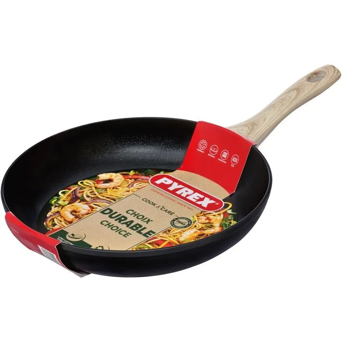Eine schwarze Pyrex-Bratpfanne mit Holzoptik-Griff und Produktlabel über Nudeln mit Meeresfrüchten.