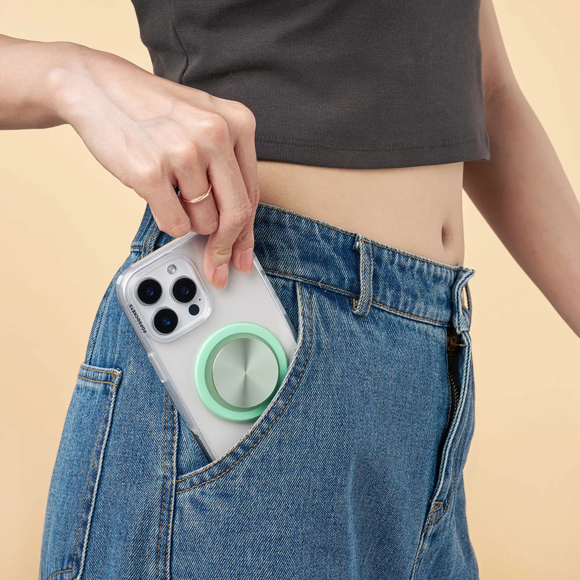 Eine Person steckt ein Smartphone mit hellgrünem Griff in die Vordertasche ihrer Blue Jeans.