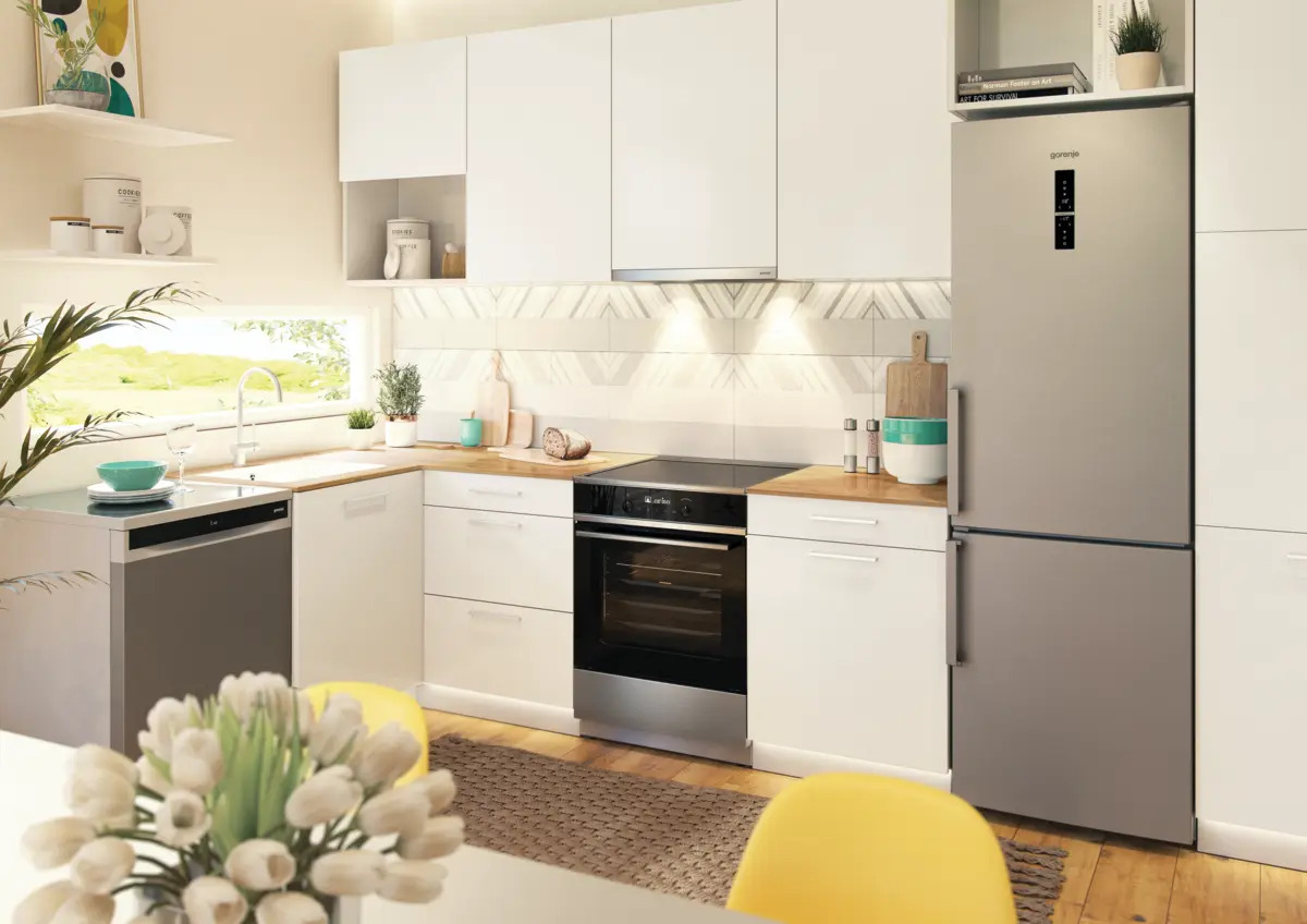 Moderna cocina con gabinetes blancos, encimeras de madera, electrodomésticos de acero inoxidable y refrigerador gris.