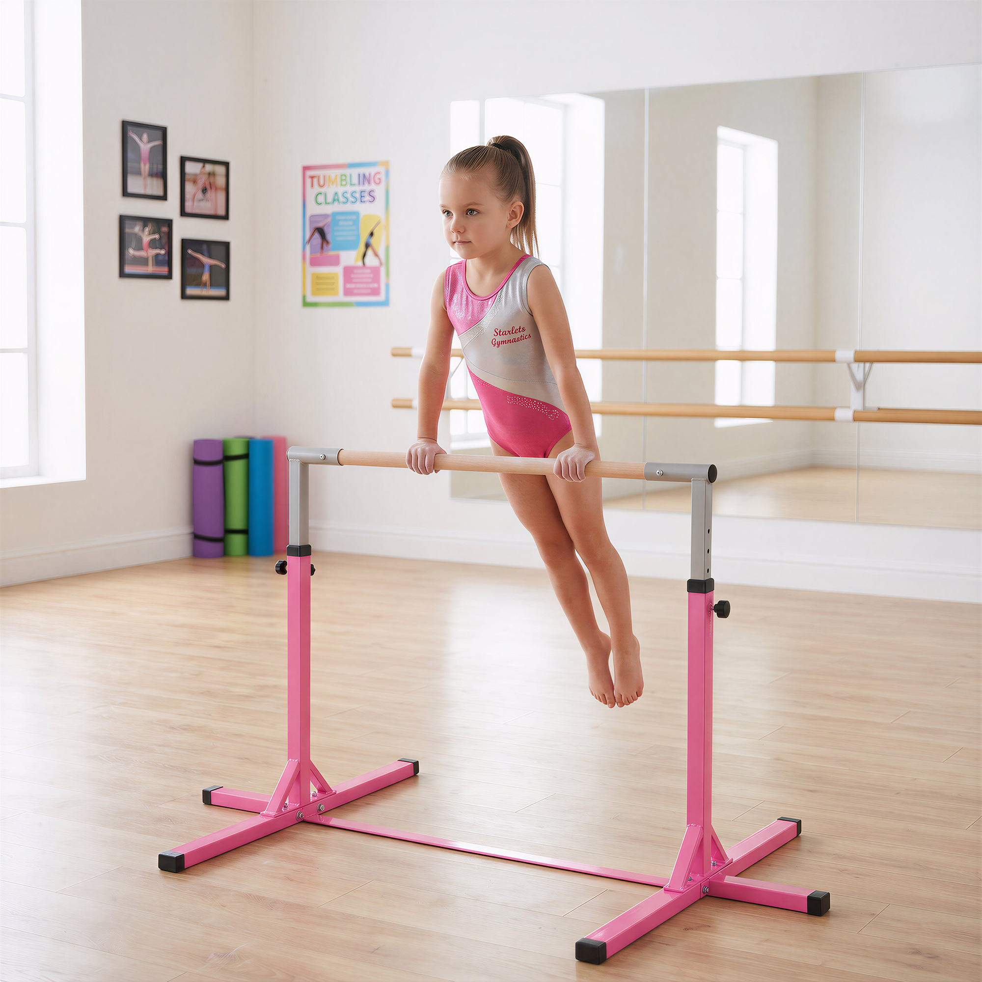 Una niña con un maillot rosa se agarra a una barra de gimnasia en un estudio con espejo.