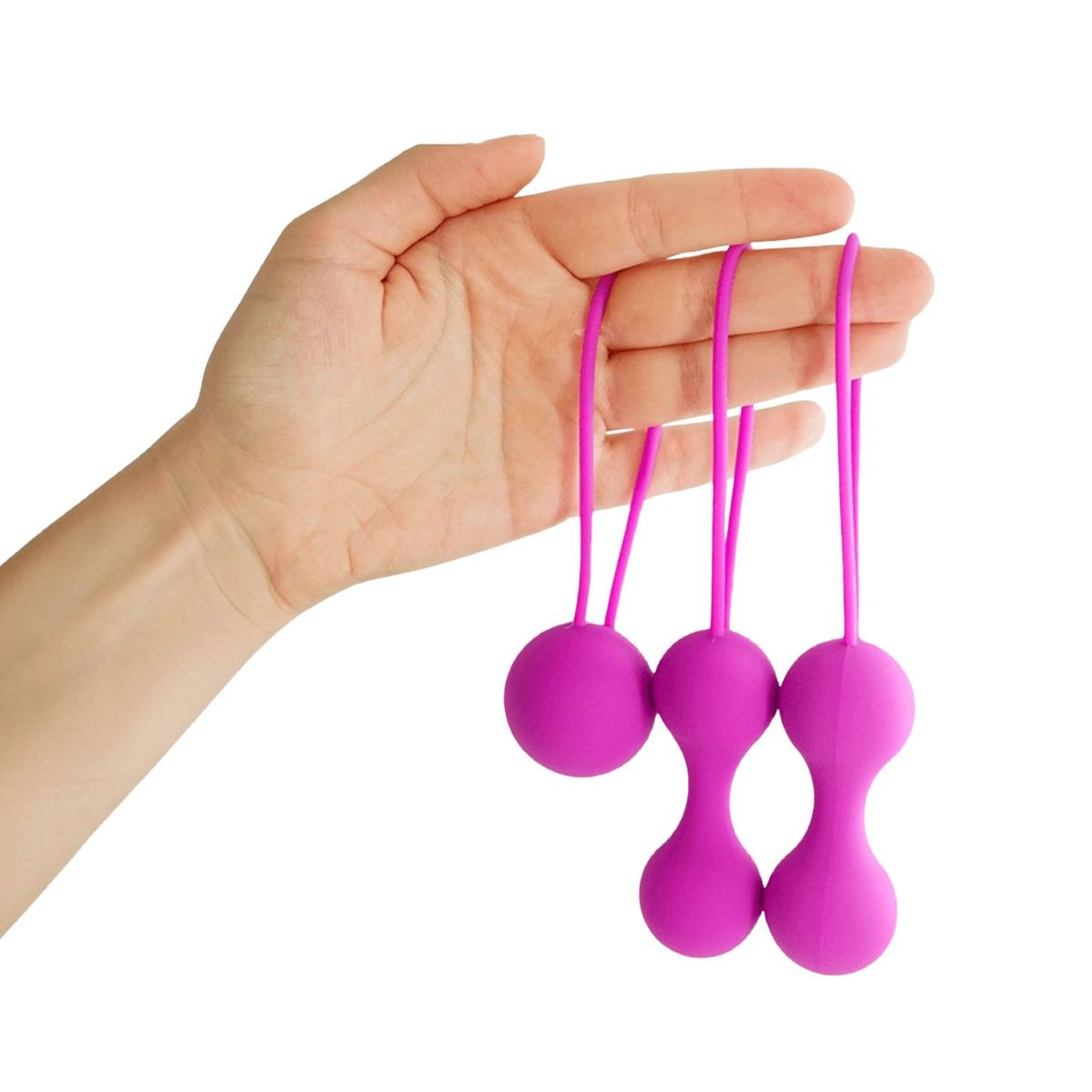 Eine Hand hält drei pinke Silikonkugeln mit integrierten Schlaufen gegen einen weißen Hintergrund.