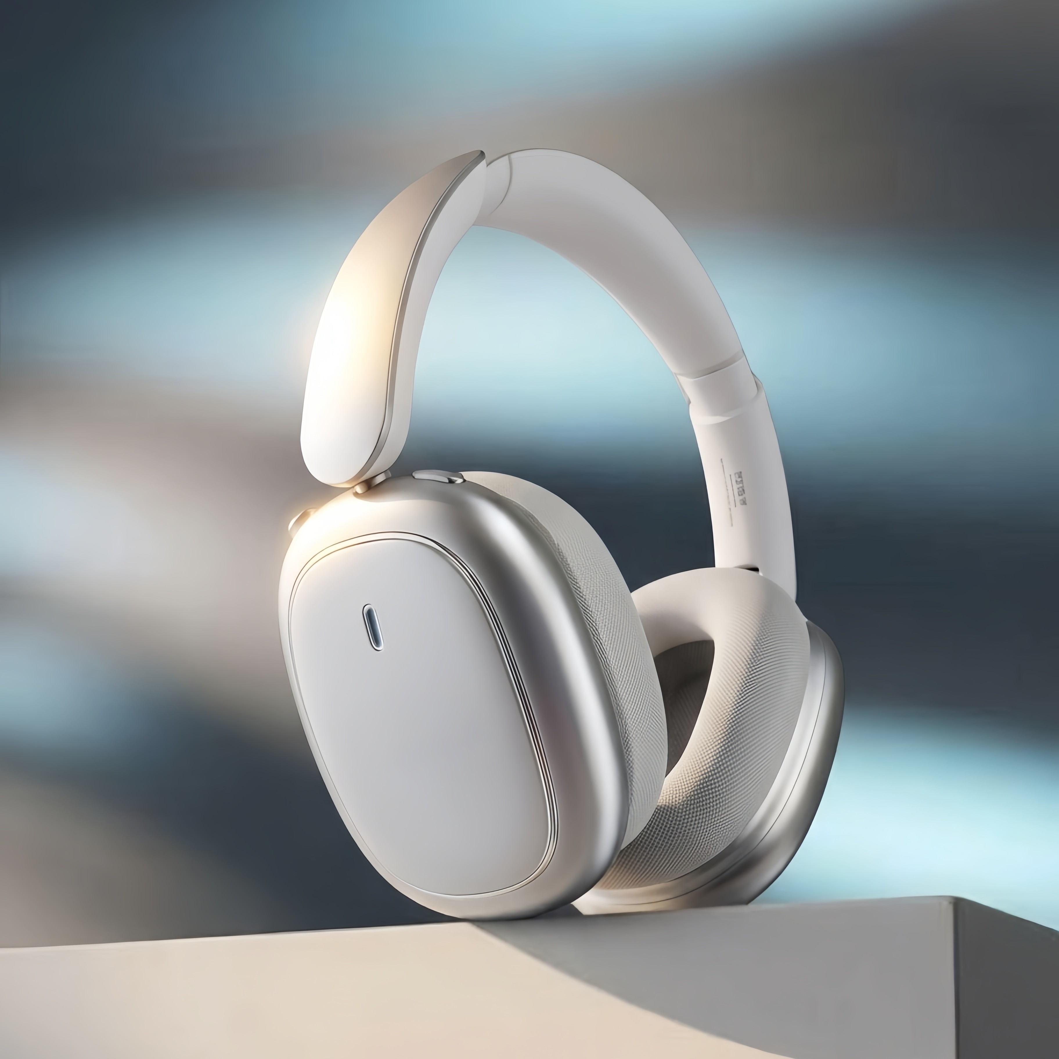 Modernos auriculares supraurales blancos con detalles plateados sobre una superficie clara y fondo difuminado.