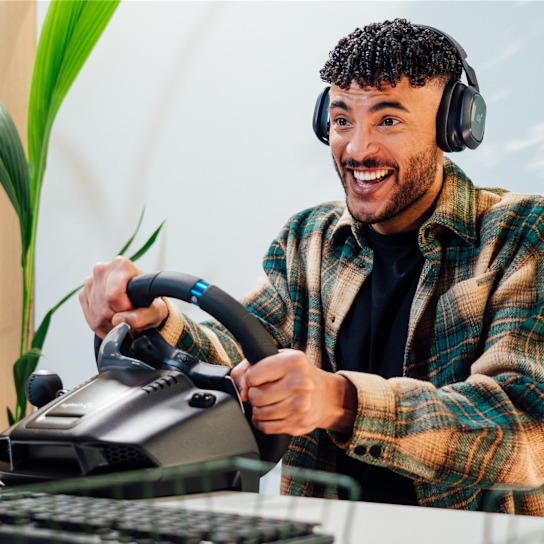 Ein glücklicher Mann mit Kopfhörern spielt ein Rennspiel am Simulator.