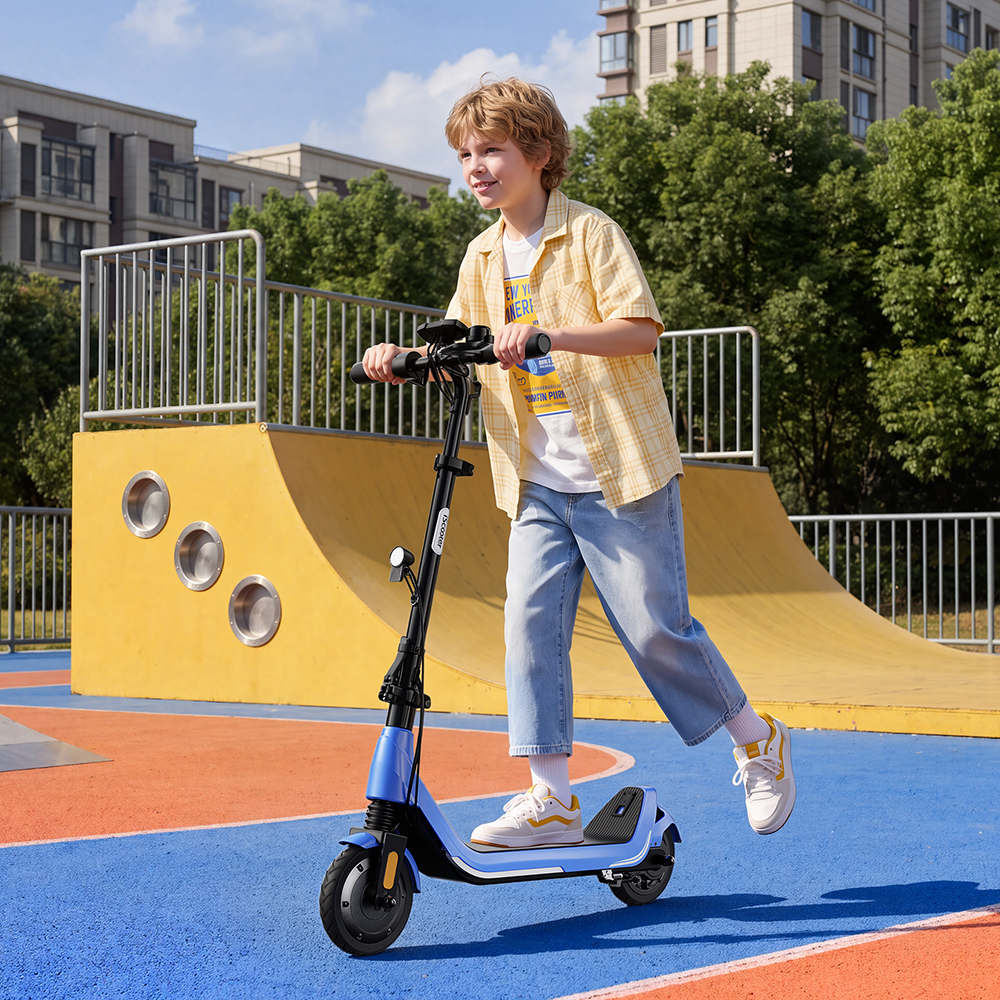 Chłopiec uśmiecha się, jadąc na niebieskiej hulajnodze elektrycznej w skateparku z żółtą rampą i budynkami w tle.