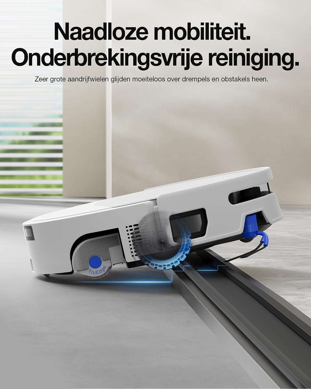 Een witte robotstofzuiger rijdt soepel over een zwarte deurdrempel in een moderne kamer.