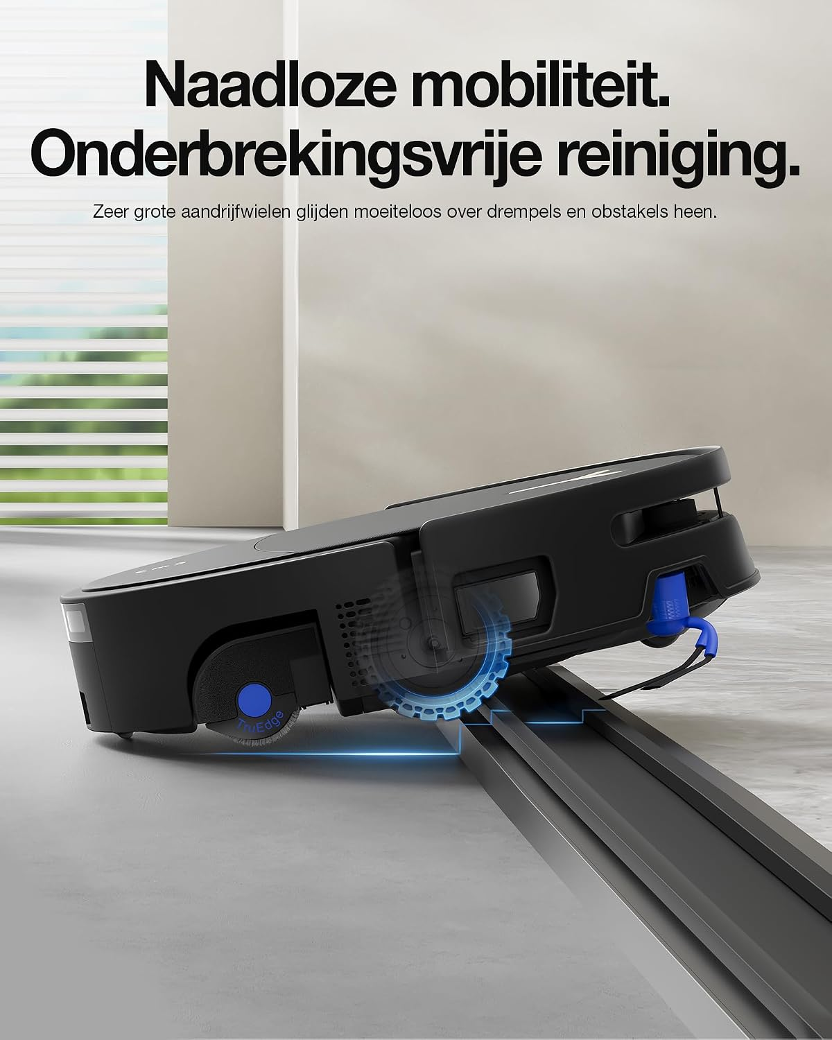 Een zwarte robotstofzuiger rijdt soepel over een verhoogde drempel in een lichte kamer.