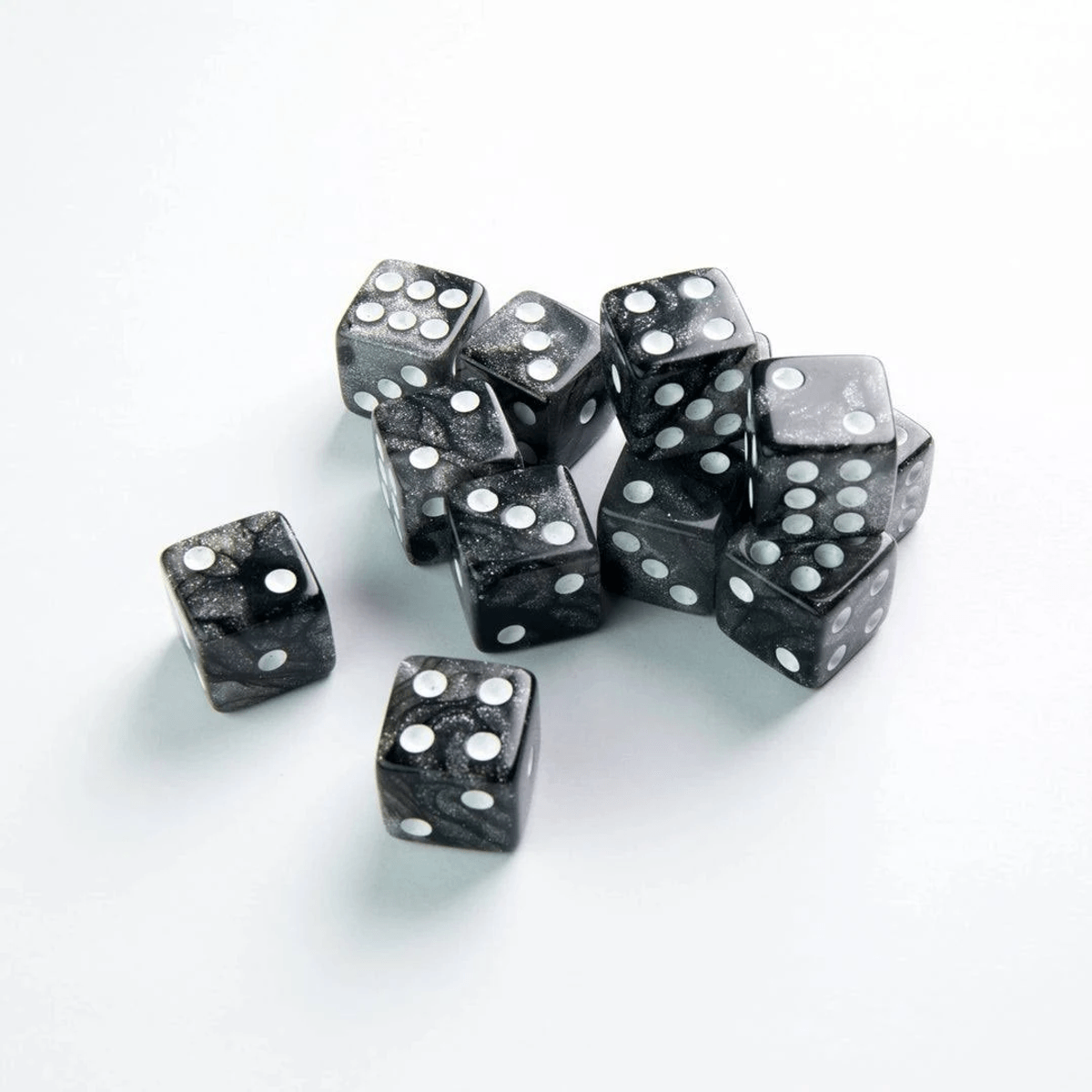 Un grupo de dados negros y brillantes con puntos blancos dispersos sobre una superficie clara y lisa.