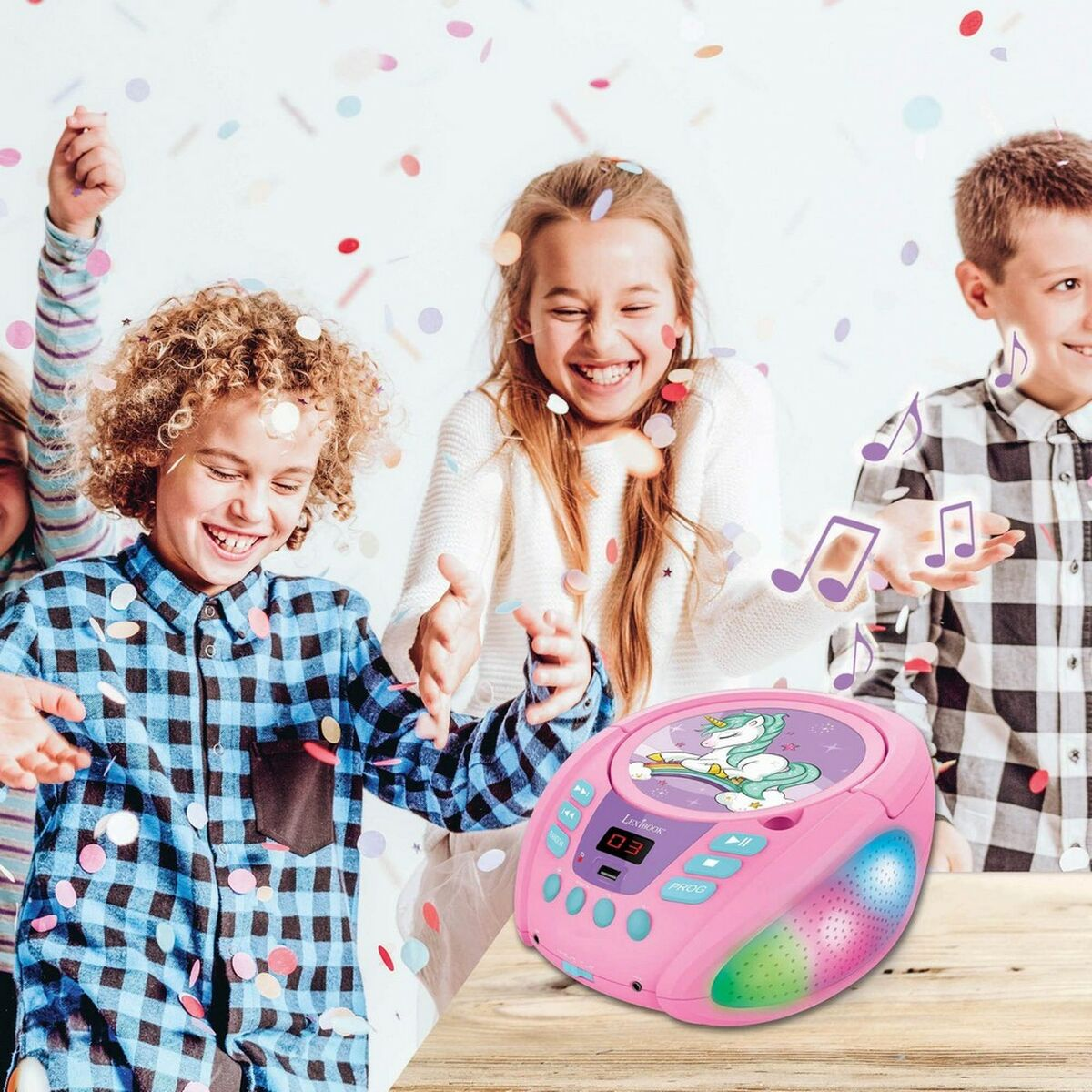 Glückliche Kinder feiern unter Konfetti, neben einem rosa Einhorn-Musikplayer auf einem Tisch.