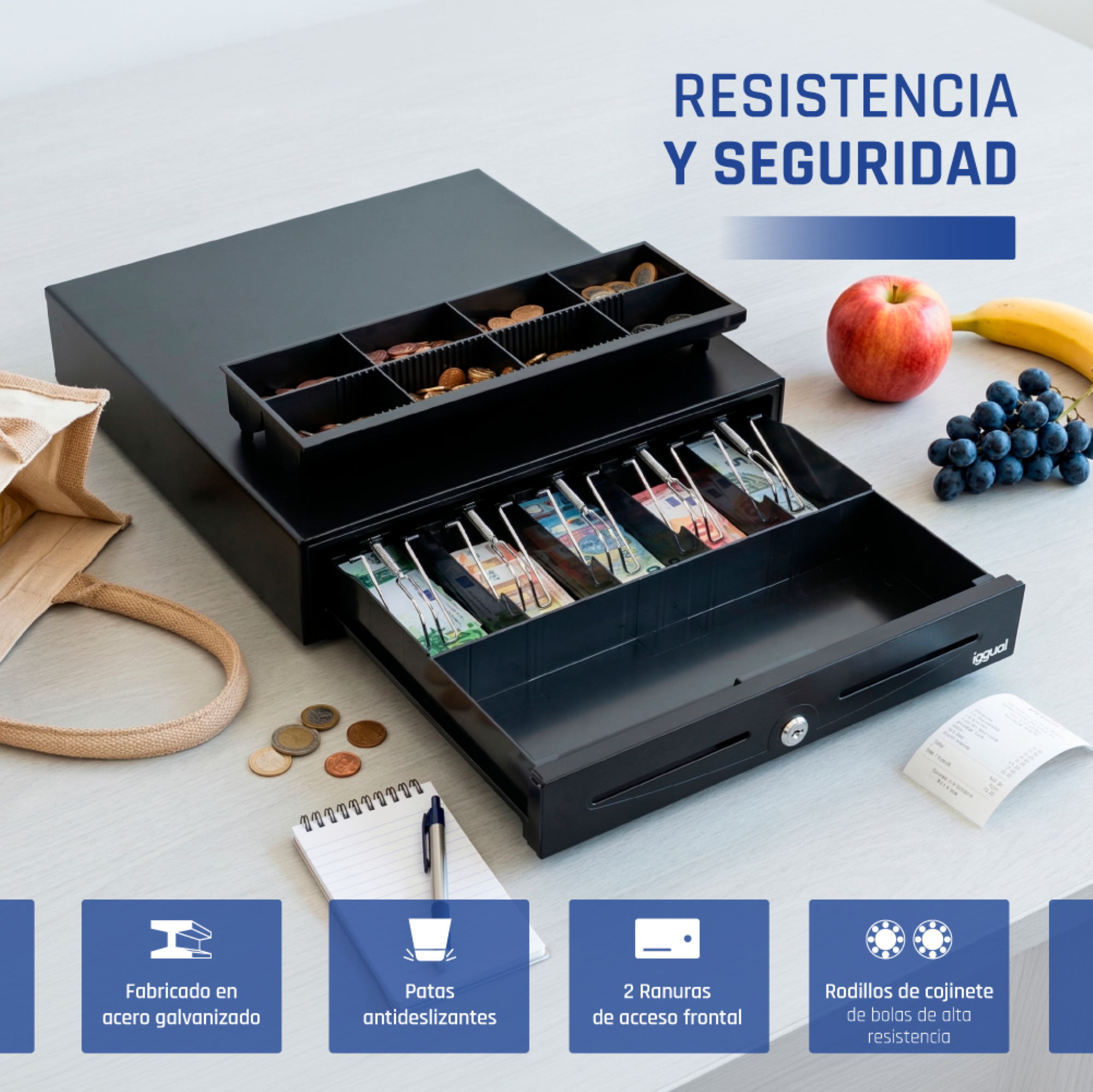 Caja registradora negra en una mesa con fruta, libreta e infografías.
