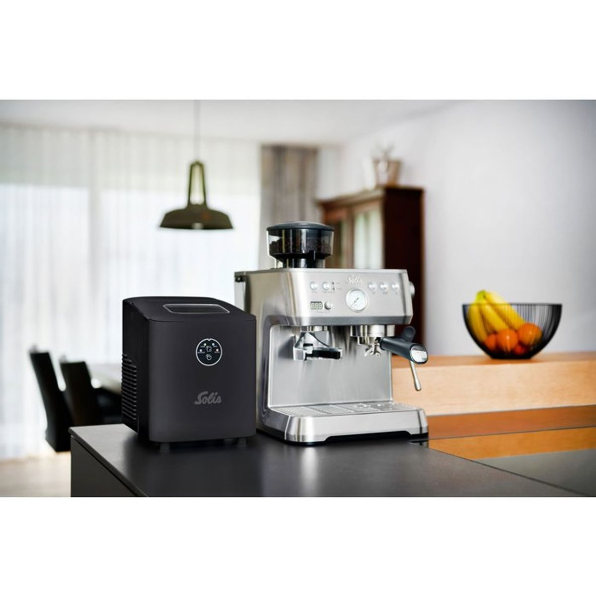 Eine schwarze Eismaschine und eine silberne Espressomaschine stehen auf einer Küchentheke.
