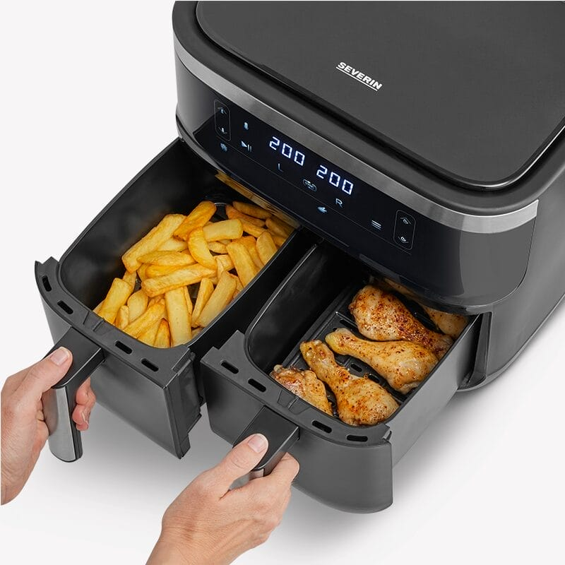 Een zwarte dubbele Airfryer met friet in de ene mand en kippenbouten in de andere.