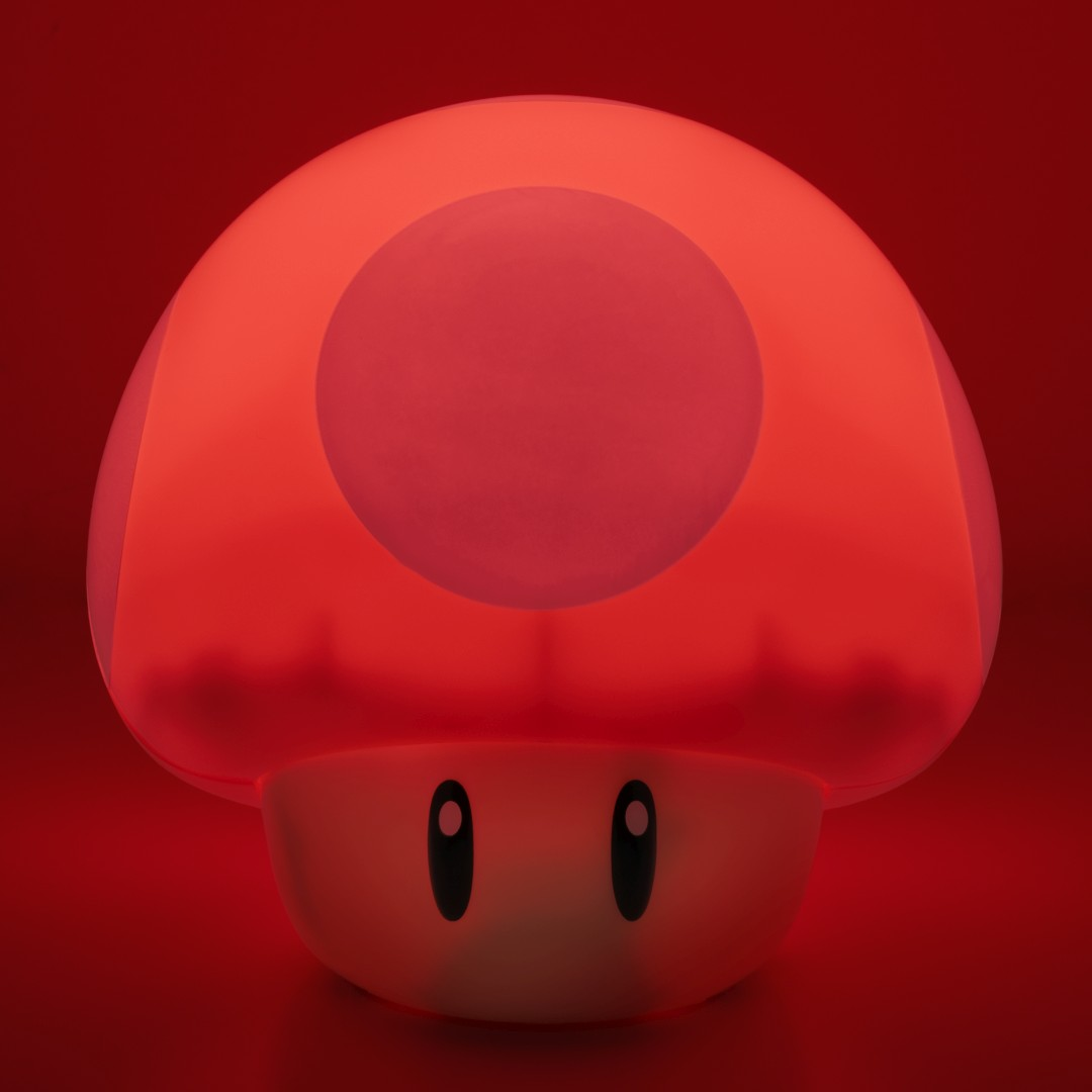 Eine leuchtende rote Pilzlampe mit weißen Flecken und großen schwarzen Augen vor rotem Hintergrund.