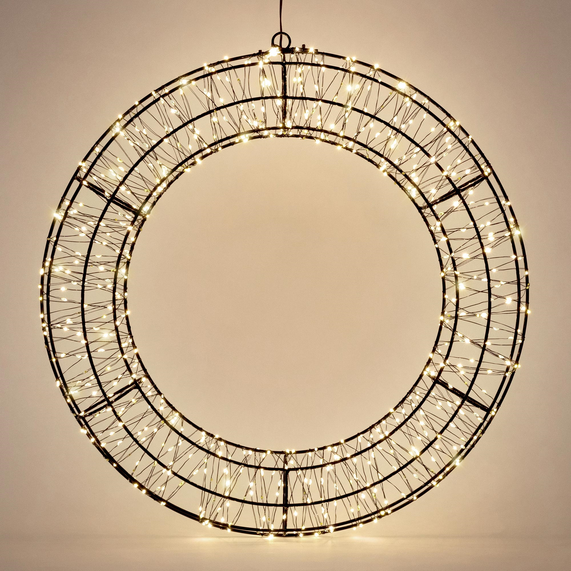Ein großer, runder, schwarzer Metallring mit vielen kleinen, warmen LED-Lichtern auf einem neutralen Hintergrund.