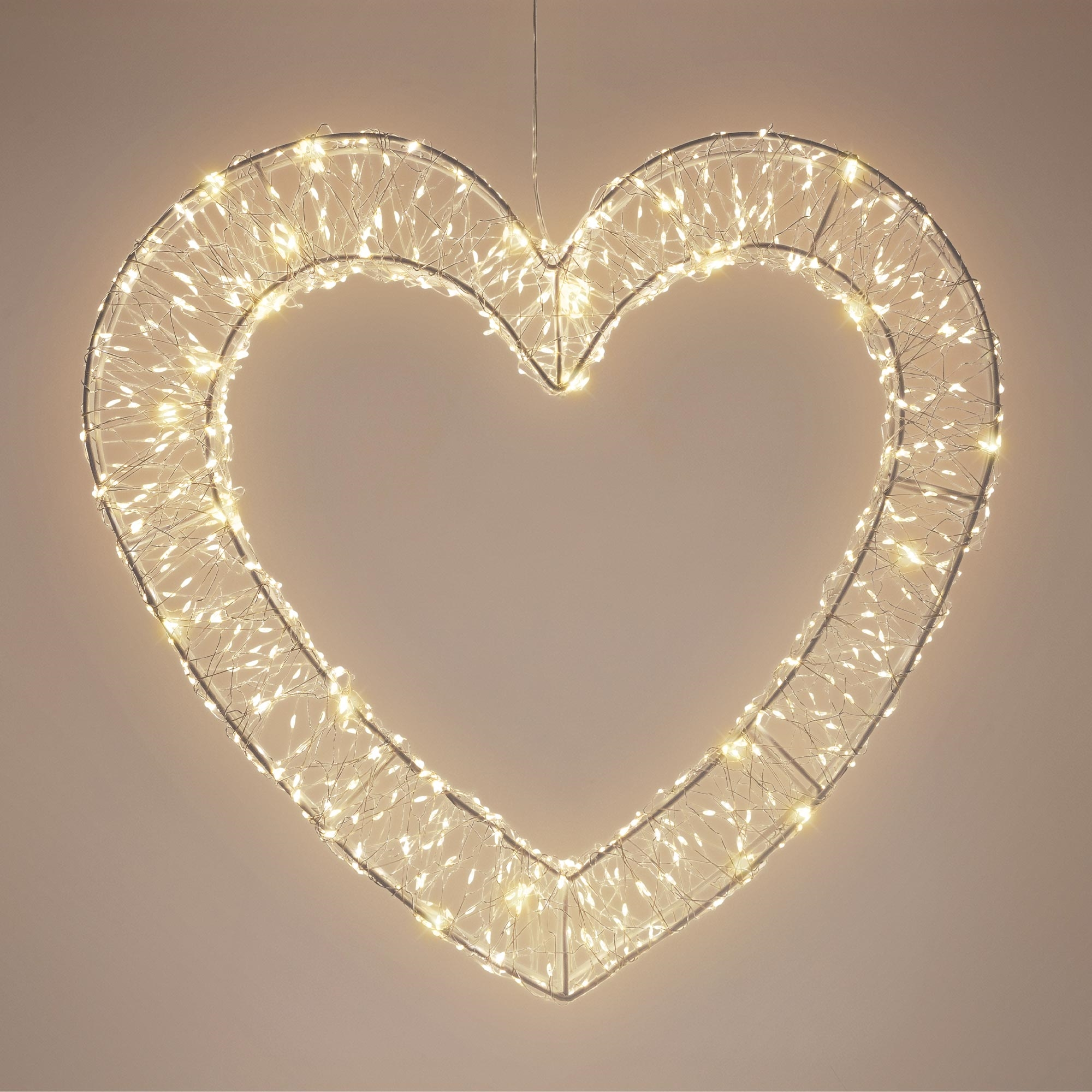 Ein großes, hängendes Herz aus Draht, das mit warmen, weißen Lichterketten beleuchtet ist.