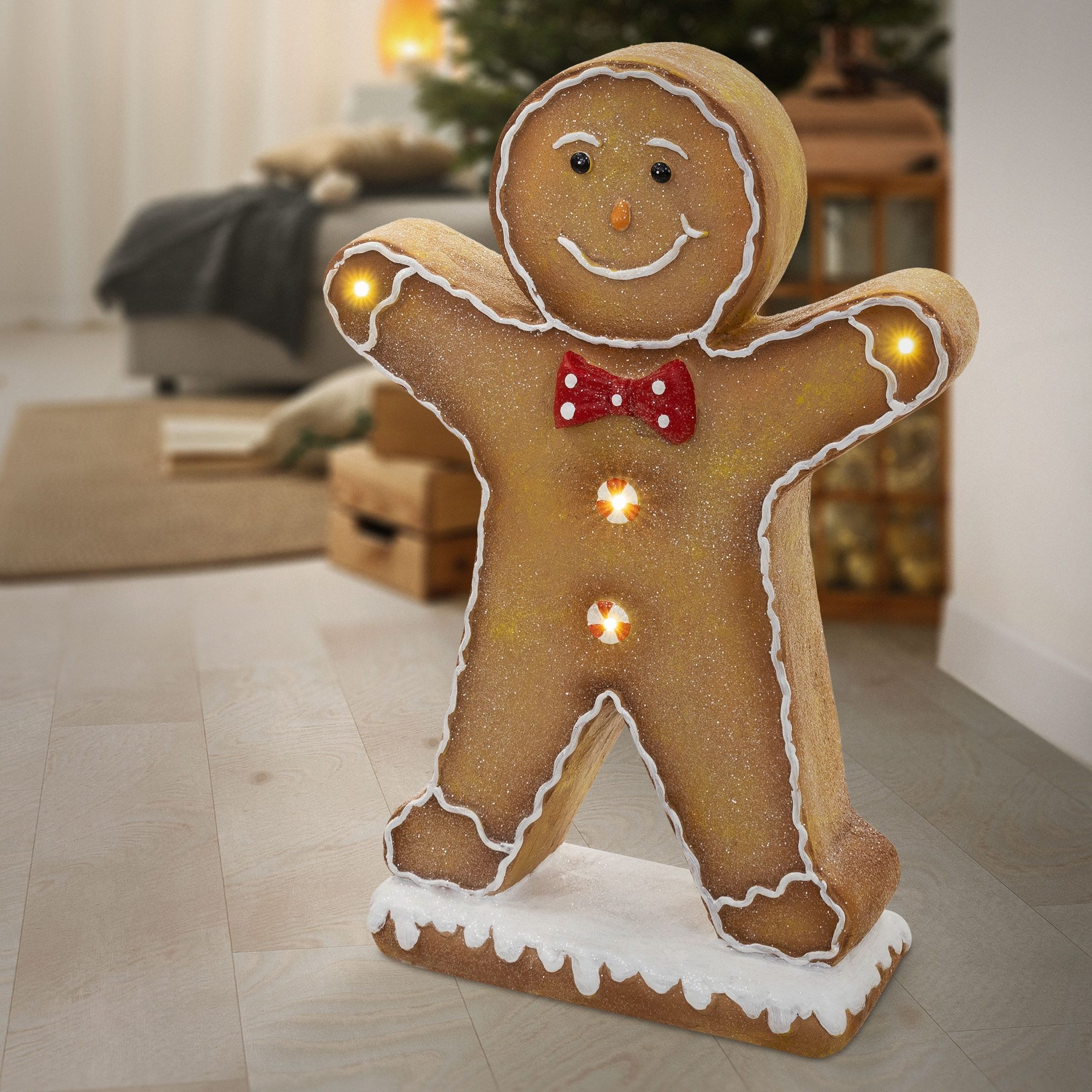 Beleuchtete Lebkuchenmann-Figur mit roter Schleife und Icing-Details im Wohnzimmer.