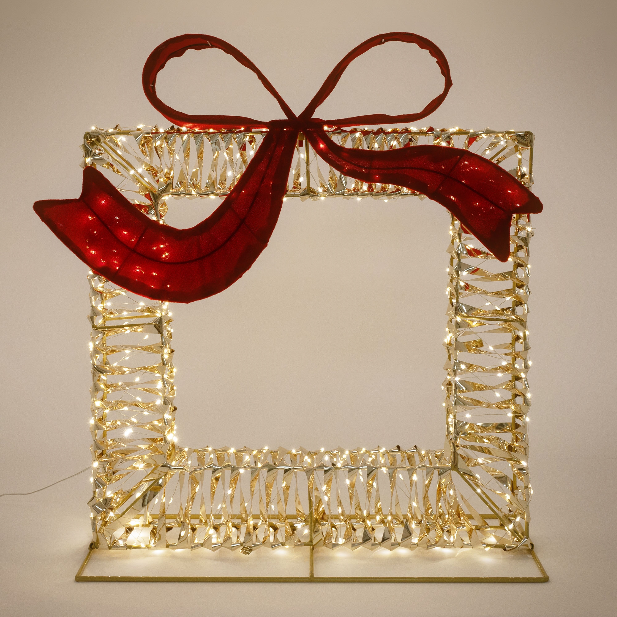 Eine quadratische, beleuchtete Weihnachtsgeschenk-Dekoration mit einer großen roten Schleife oben.