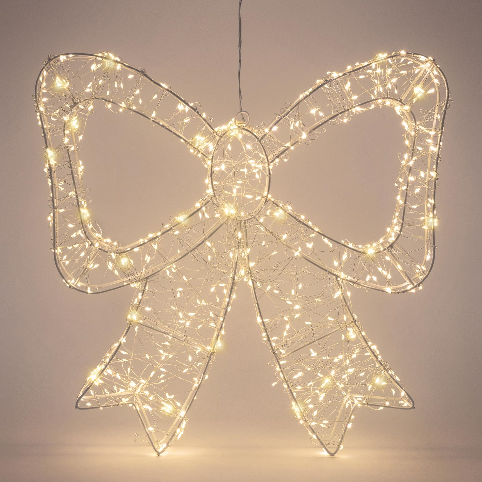 Eine leuchtende Drahtschleifen-Dekoration mit warmweißen Lichterketten vor einem neutralen Hintergrund.