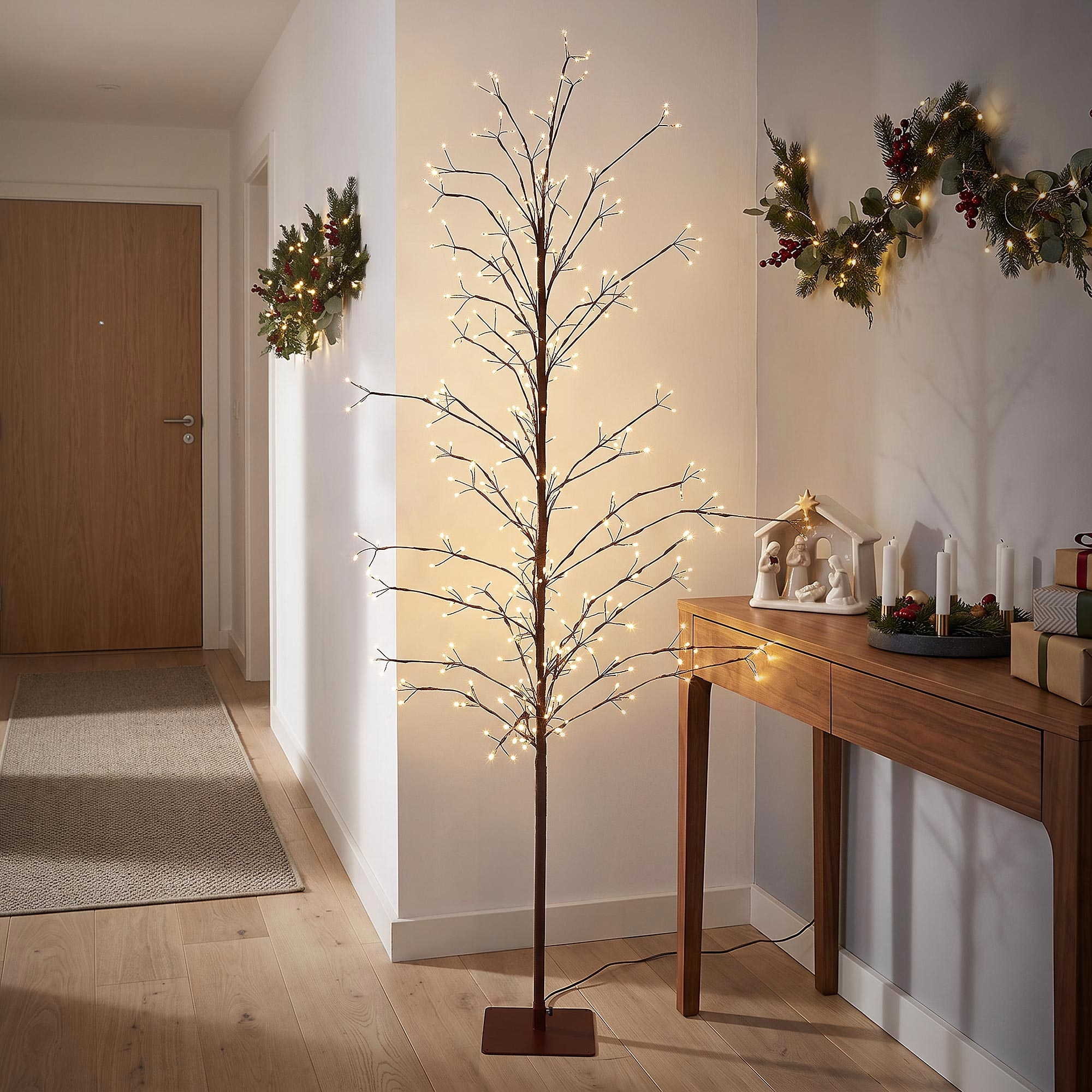 Beleuchteter LED-Lichterbaum in einem Flur mit festlicher Dekoration auf der Holzzusammenstellung.