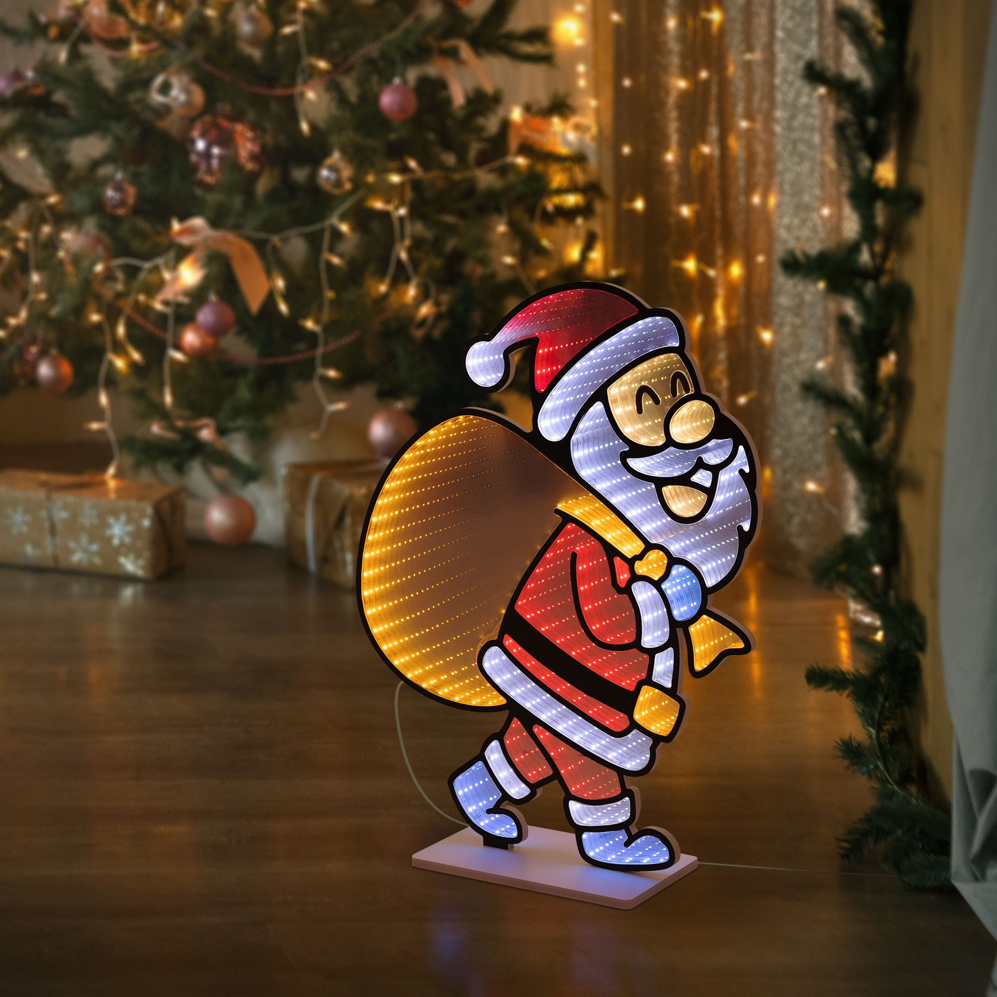Eine leuchtende Weihnachtsmann-Silhouette mit großem goldenem Sack steht drinnen vor einem Tannenbaum.