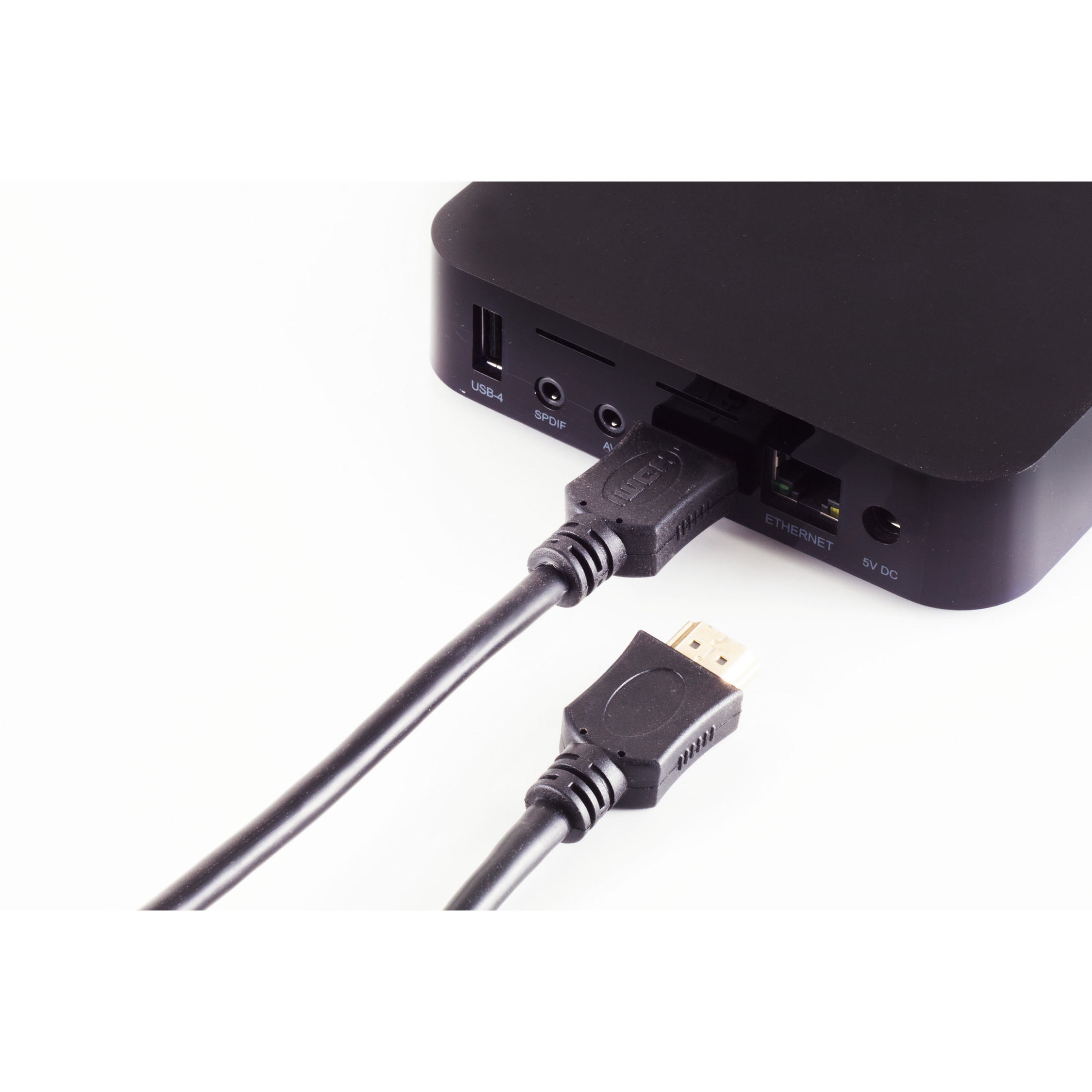 Eine schwarze Medienbox mit eingestecktem HDMI-Kabel und einem weiteren Kabel darunter.