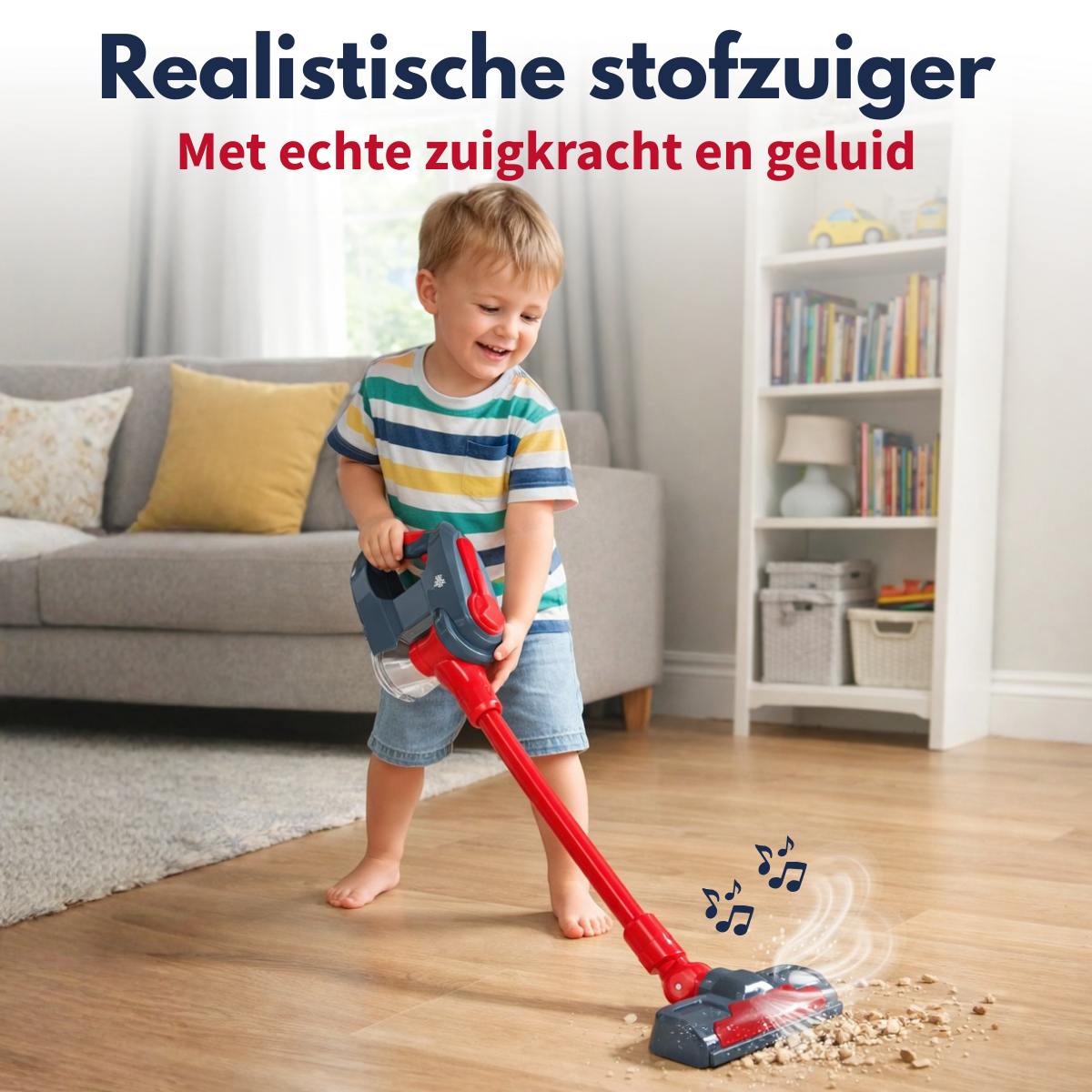 Un jeune enfant sourit en jouant avec un aspirateur jouet rouge sur un plancher en bois.