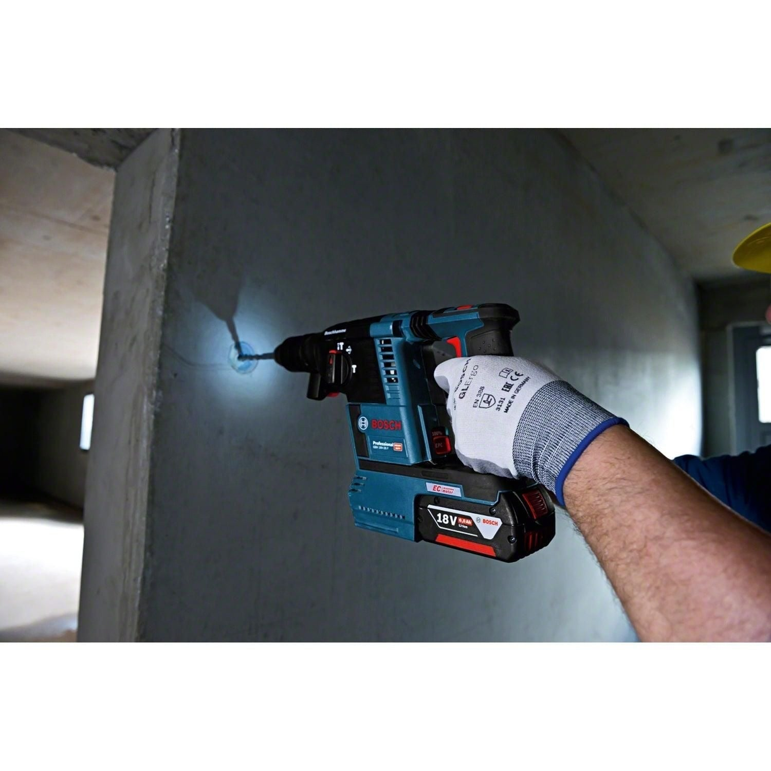 Ein Arbeiter bohrt mit einem blauen Bosch Akku-Bohrhammer ein Loch in eine Betonwand.
