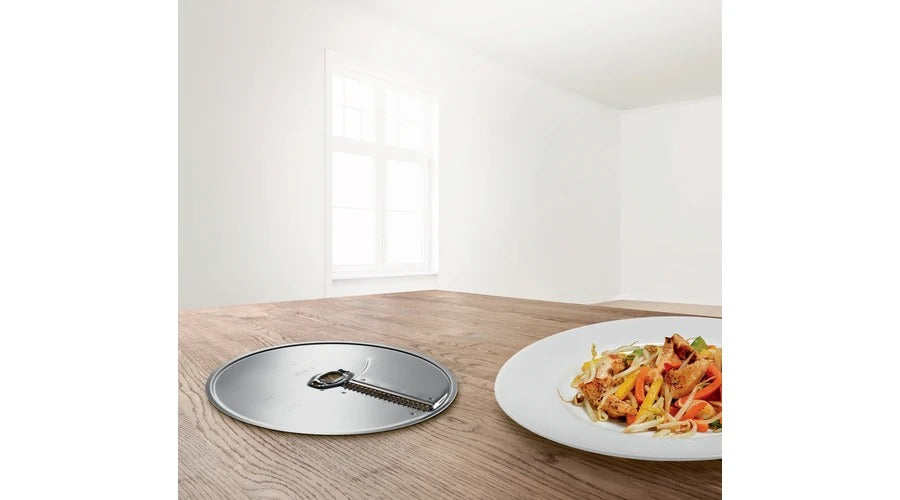 Un piatto d'acciaio rotondo su un tavolo di legno accanto a un piatto di verdure saltate e pollo.