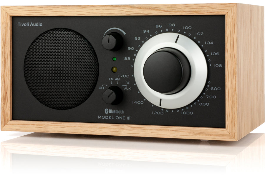 Ein Tivoli Audio Model One BT Radio in hellem Holzgehäuse mit schwarzer Front, schwarzem Lautsprecher und silbernem Regler.