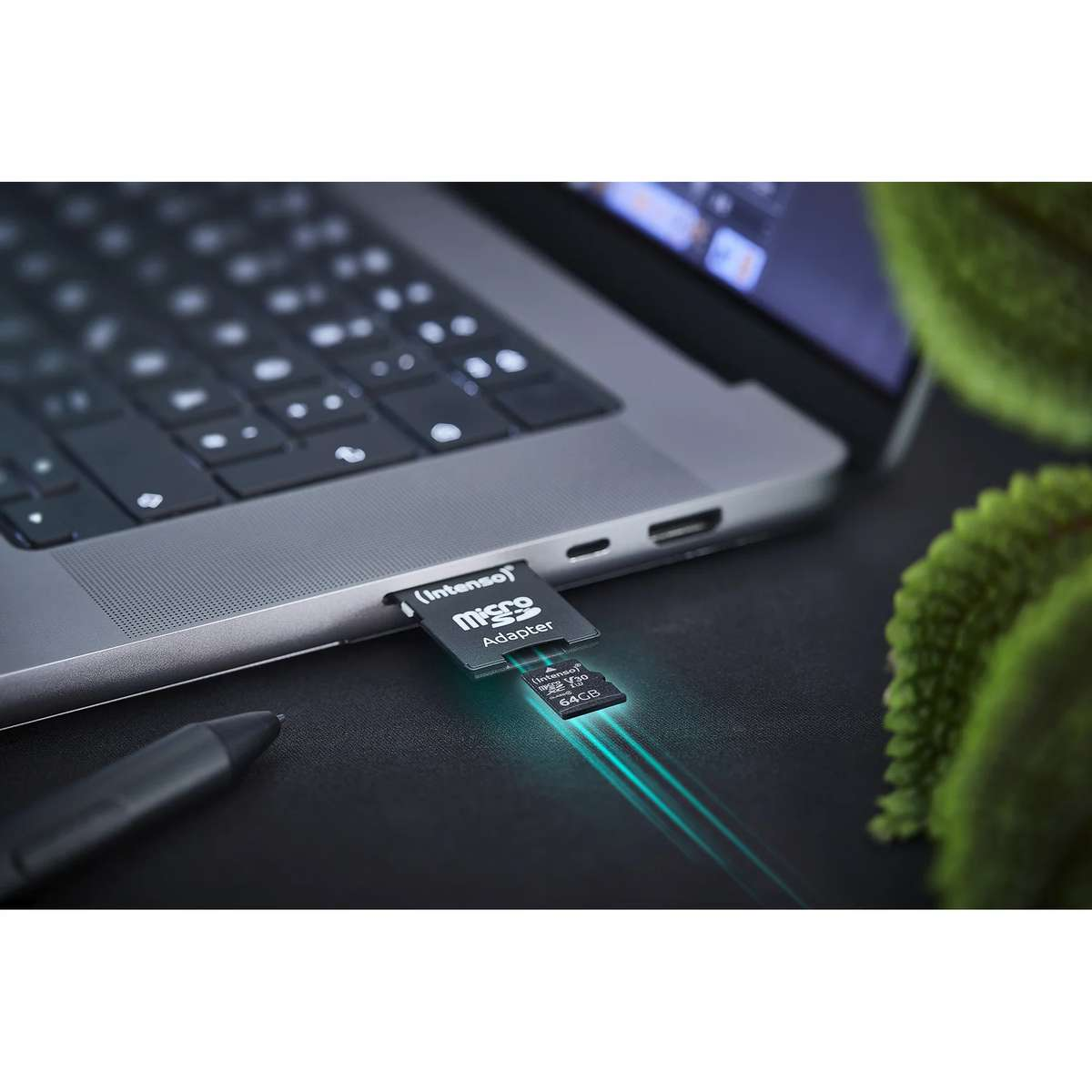Una tarjeta microSD y un adaptador insertados en una ranura de laptop, iluminados con luz azul.