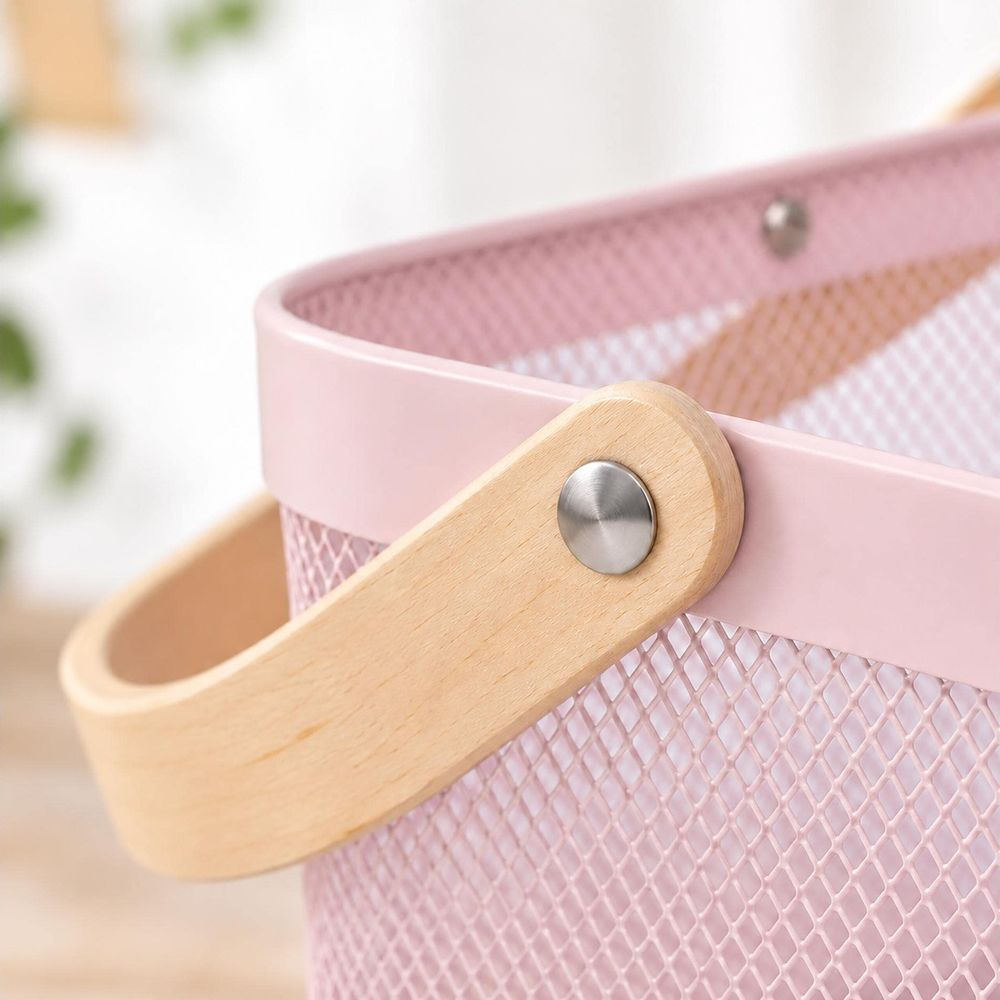Nahaufnahme eines rosa Aufbewahrungskorbs aus Netz mit hellem Holzgriff, befestigt durch eine Niete.