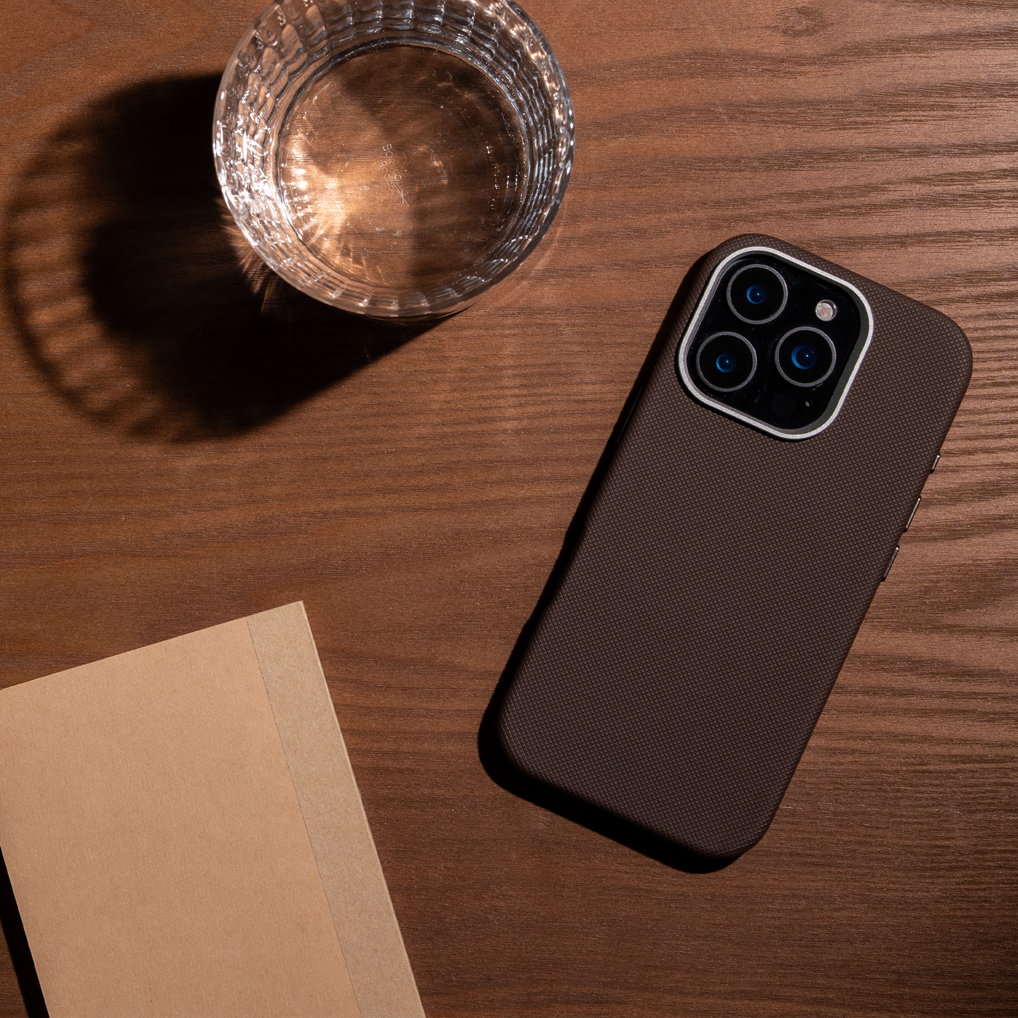 Un smartphone, un verre d'eau et un carnet reposent sur une surface en bois.