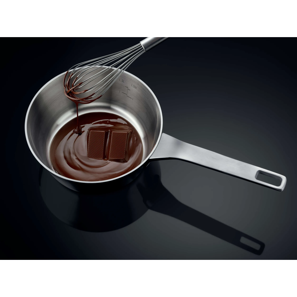 Una frusta fa gocciolare cioccolato fuso in una casseruola in acciaio inox con blocchi di cioccolato.