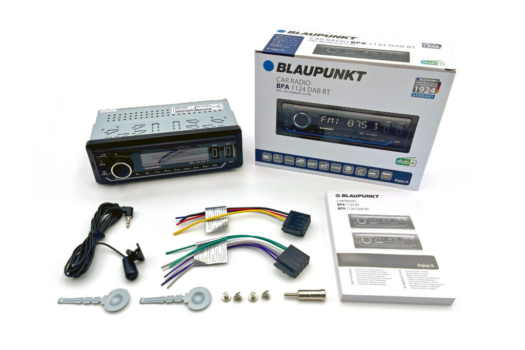 Autoradio Blaupunkt con scatola, cavi, microfono, manuale e materiale di montaggio su sfondo bianco.