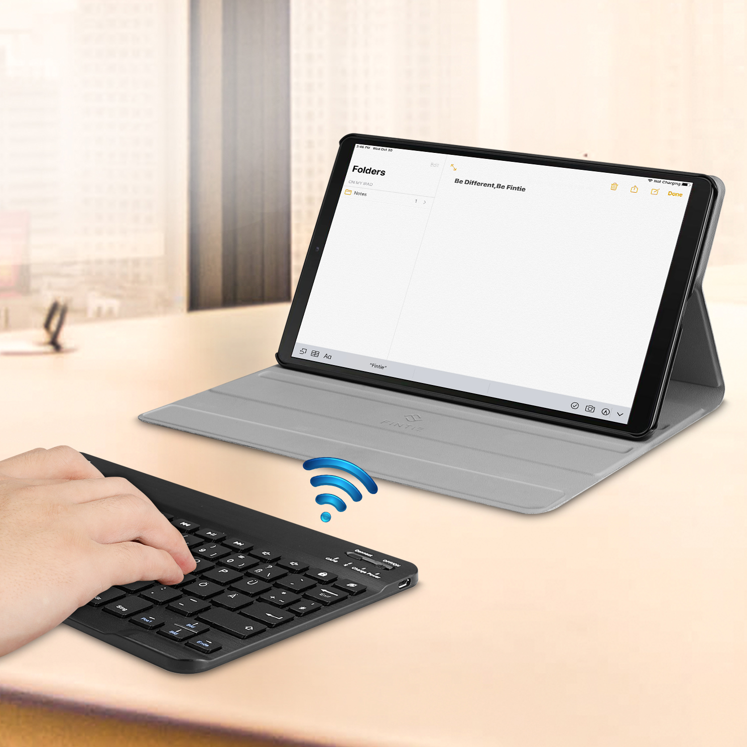 Person tippt auf einer schwarzen Tastatur, Tablet zeigt Dokument.
