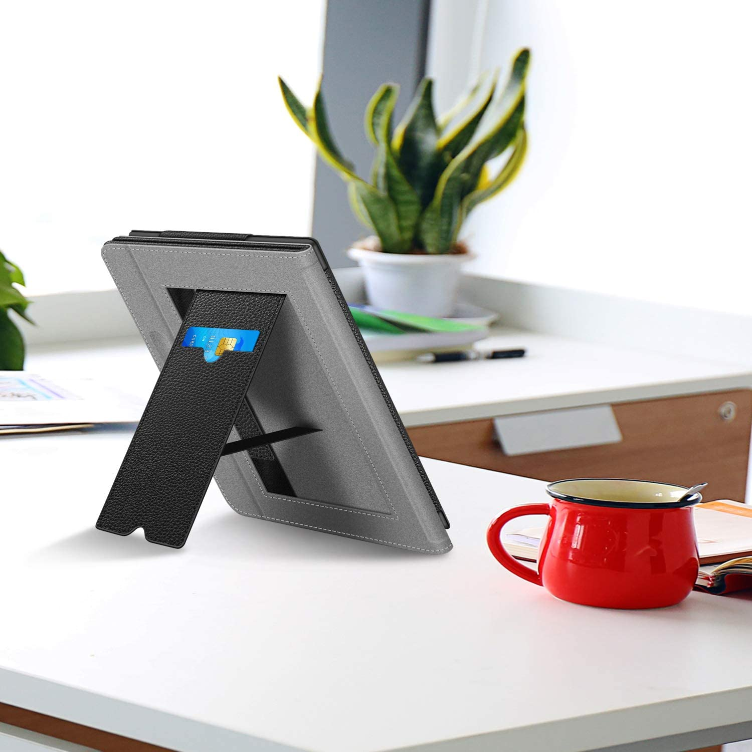 Tablet im Ständer. Eine rote Tasse im Vordergrund. Weißer Tisch, unscharfer Hintergrund.