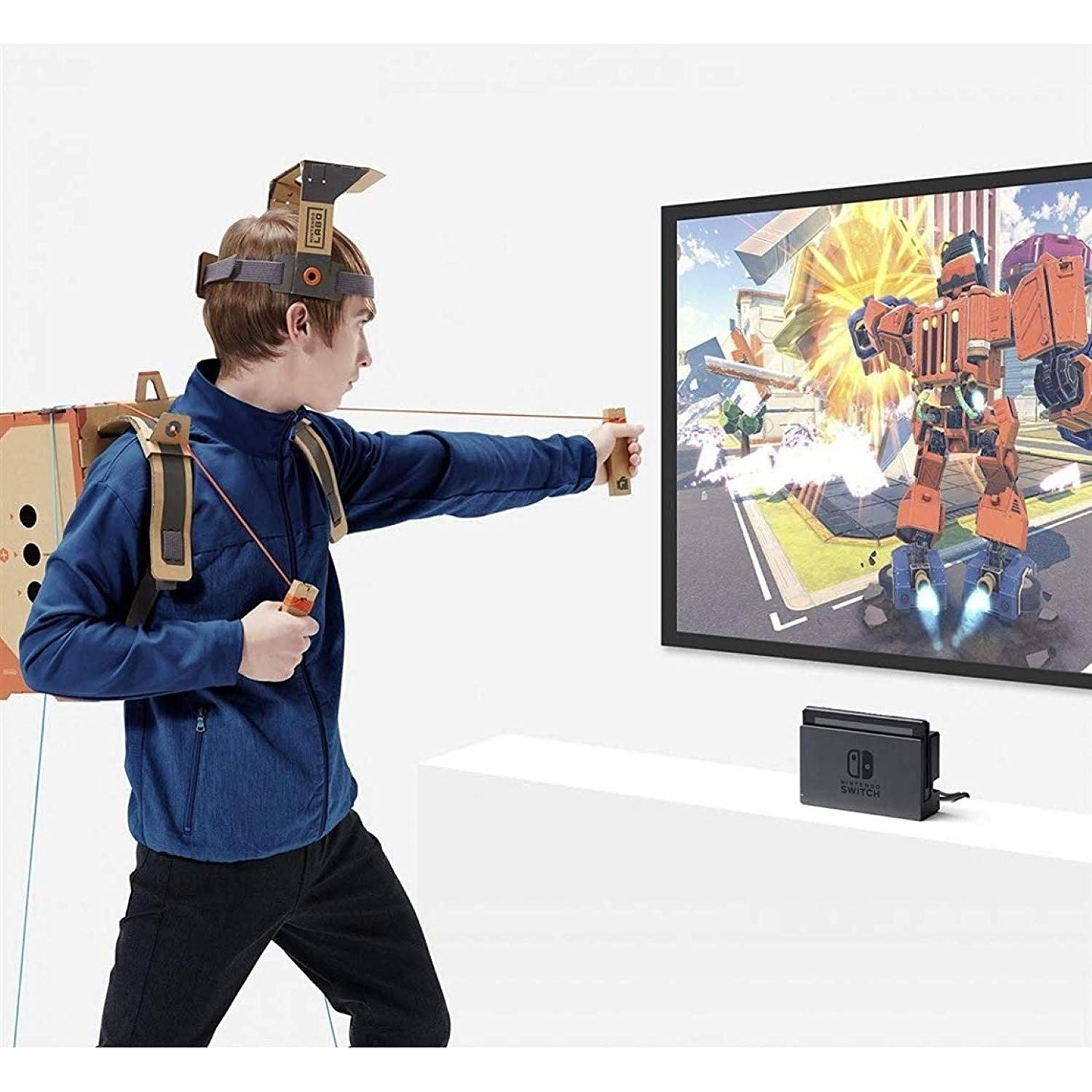 Ein Junge, der ein VR-Set aus Pappe und eine Schleuder benutzt. Ein Fernseher zeigt Spiel.
