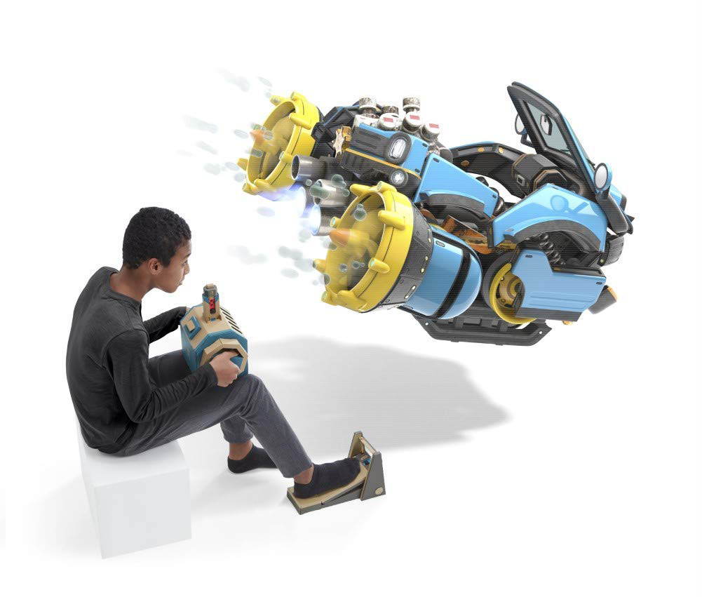 Ein Junge sitzt und bedient ein futuristisches Spielzeugfahrzeug mit Bedienfeld und Fußpedalen.