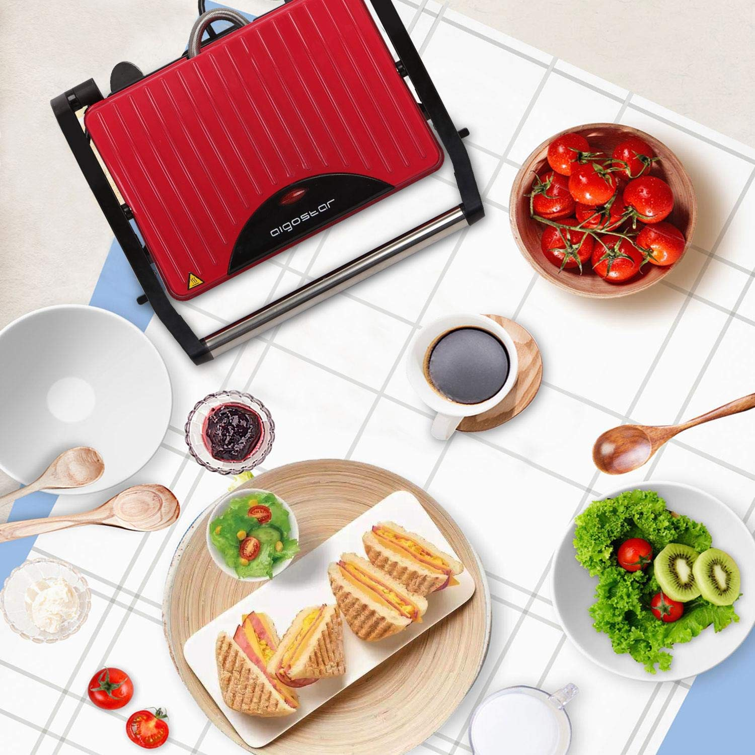Piastra panini rossa con cibo e ingredienti su una tovaglia a scacchi.