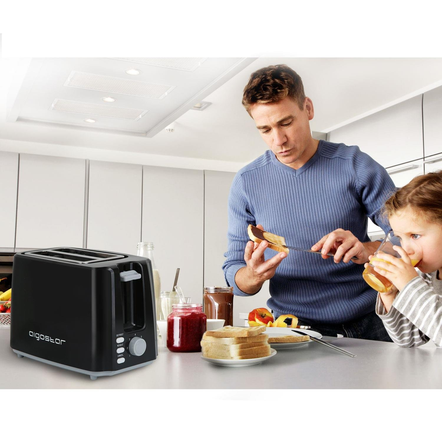 Un uomo e un bambino in cucina, vicino a un tostapane nero. L'uomo sta spalmando qualcosa sul pane.