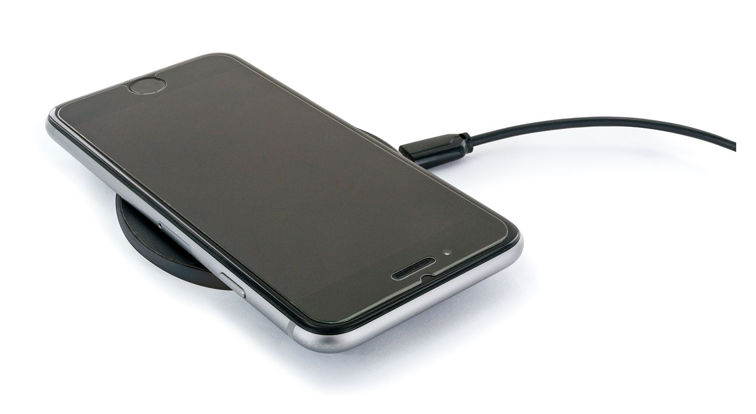 Schwarzes Smartphone auf einem schwarzen kabellosen Ladepad, weißer Hintergrund. Schwarzes Kabel.