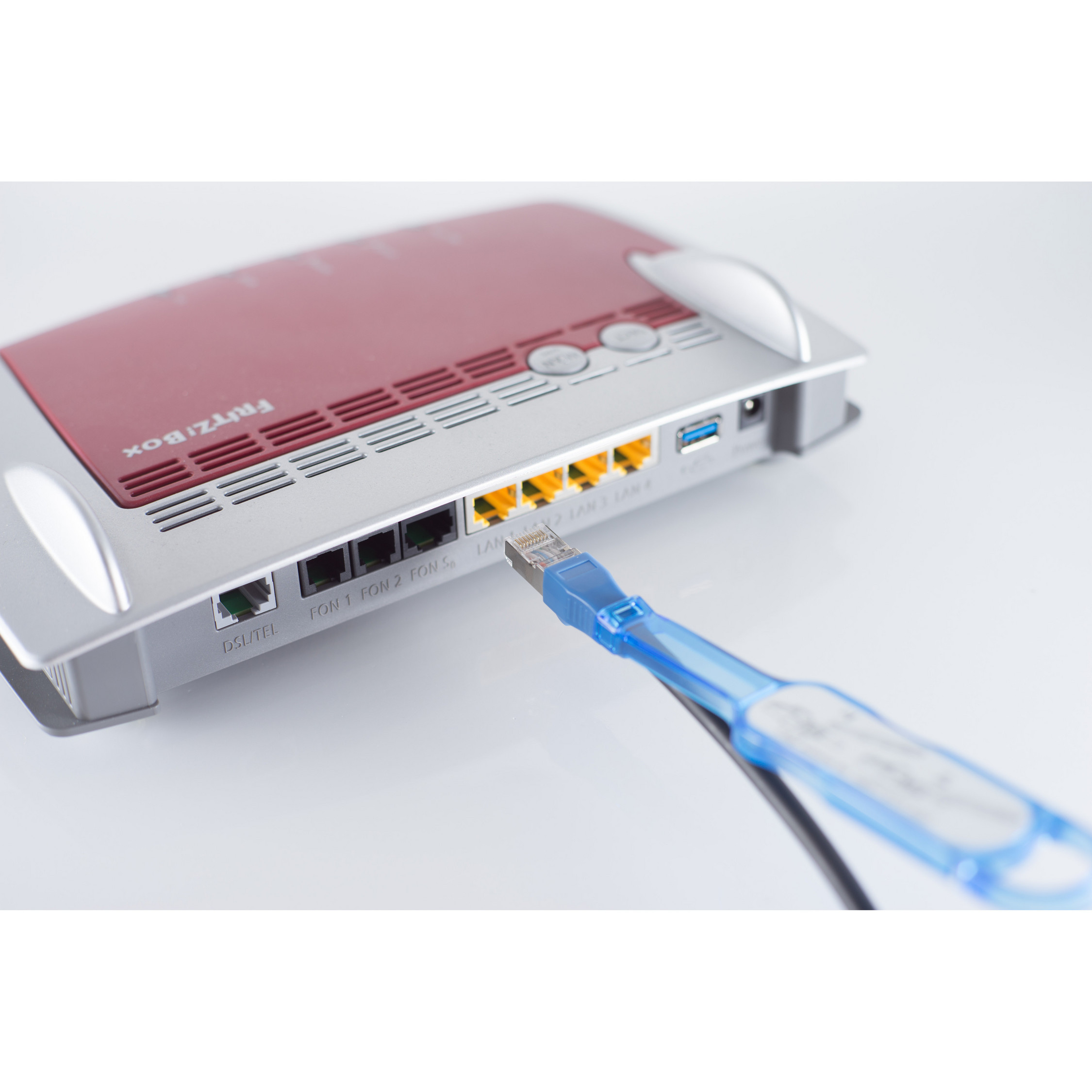 Ein roter und silberner Router mit einem blauen USB-Kabel, das in die Rückseite gesteckt ist.