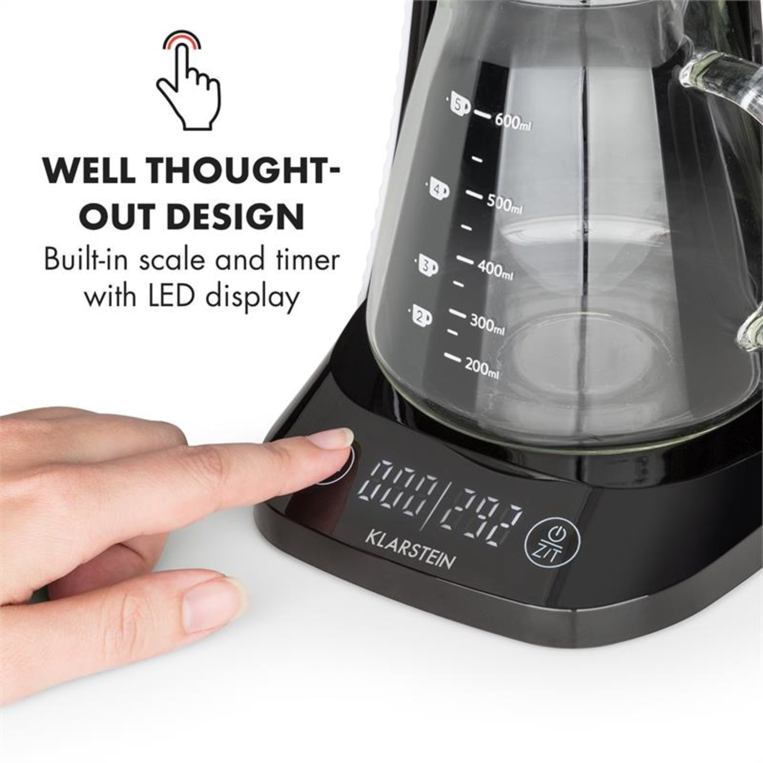 Eine Hand berührt das Bedienfeld eines Kaffeezubereiters. Der Maker hat eine Glaskaraffe mit Volumenmarkierungen. Eine Digitalanzeige zeigt Zahlen.