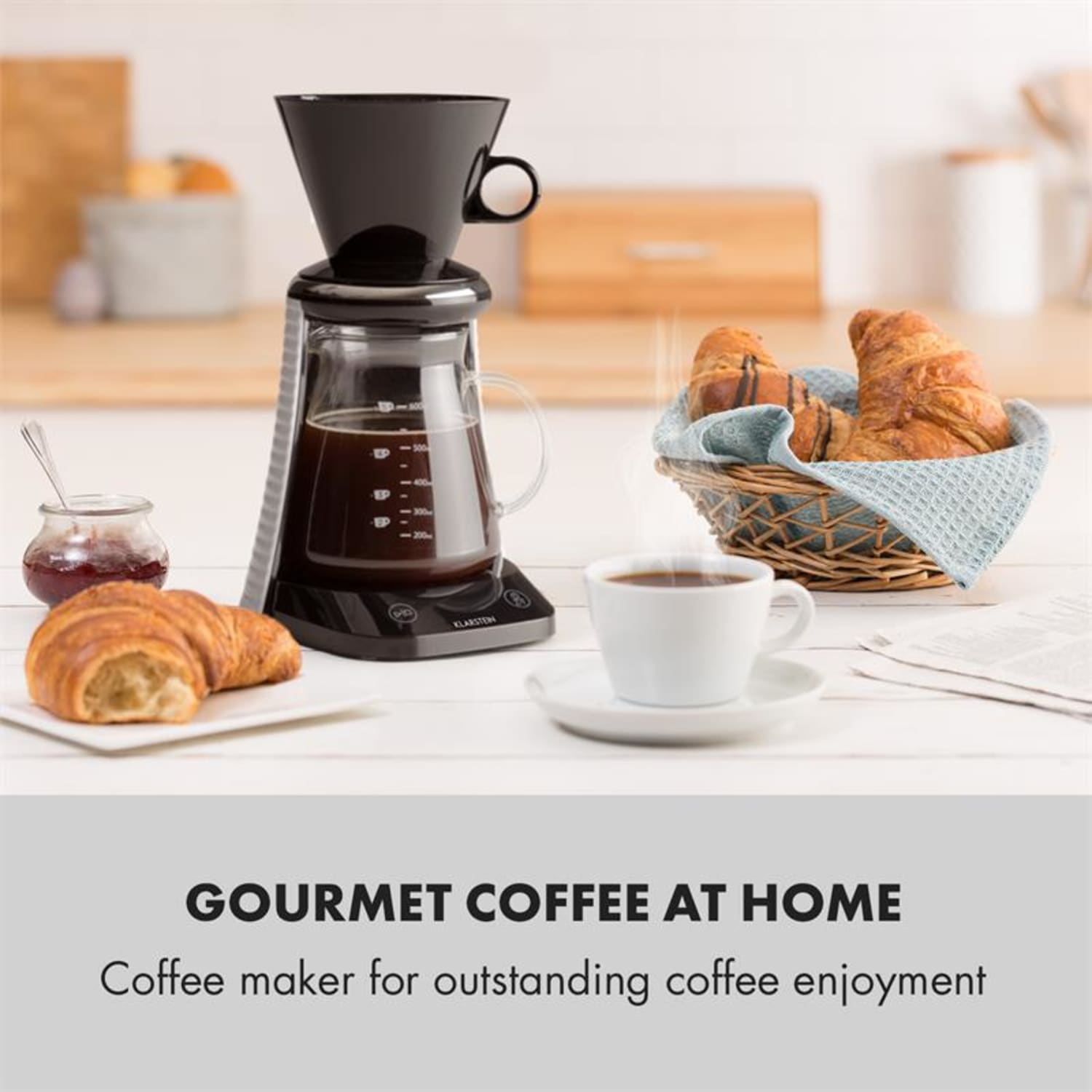 Kaffeemaschine mit Kaffee, Croissants und Marmelade auf einem weißen Tisch. Korb mit Croissants. Eine Tasse Kaffee.