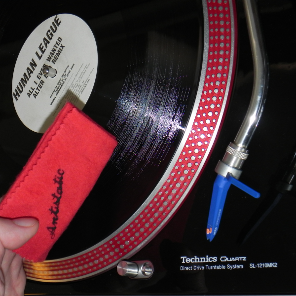Plattenspieler mit laufender Schallplatte. Rote Bürste und rote Matte. Blaue Nadel.