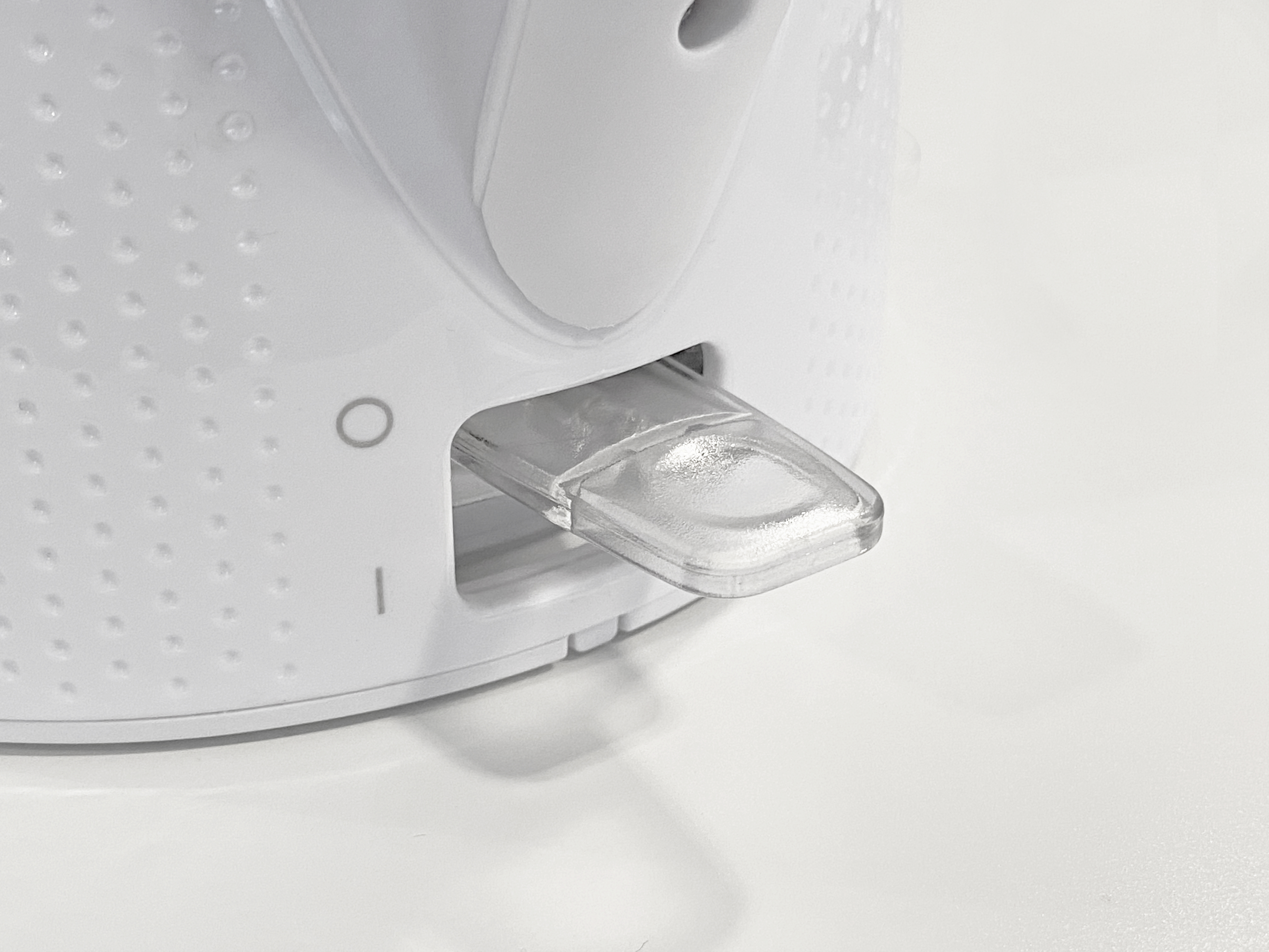 Close-up van een witte elektrische waterkoker met een doorzichtige kunststof schakelaar.