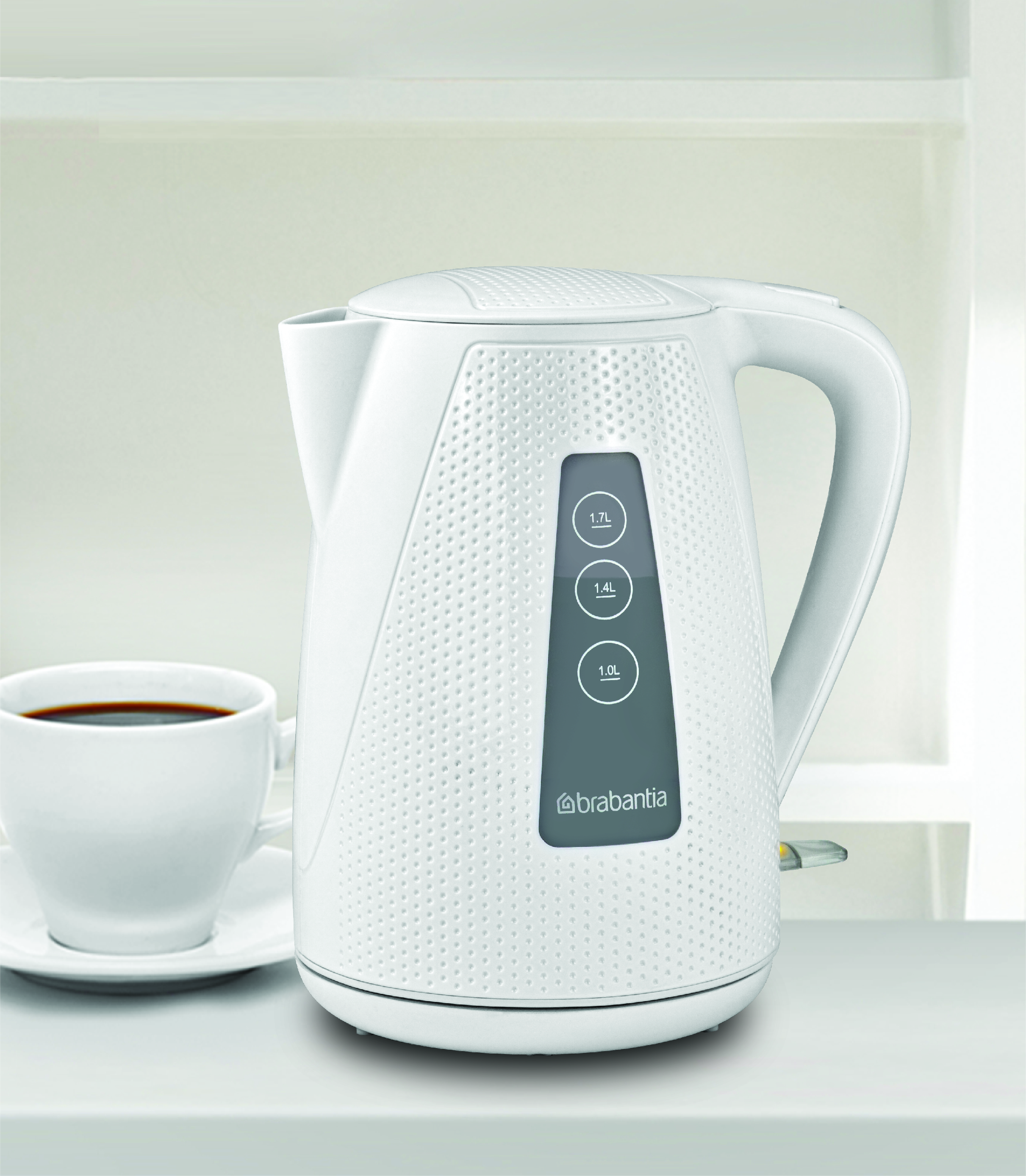 Witte elektrische waterkoker met een kopje koffie op een tafel. Het heeft waterniveau-indicatoren.