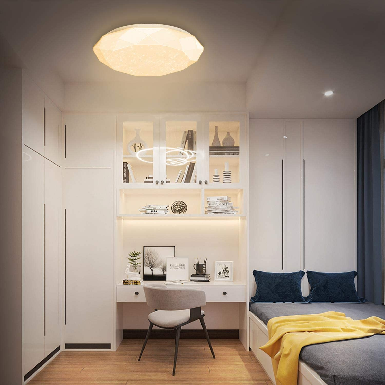 Una camera da letto moderna con pareti bianche, scrivania con sedia e letto con cuscini blu e coperta gialla.